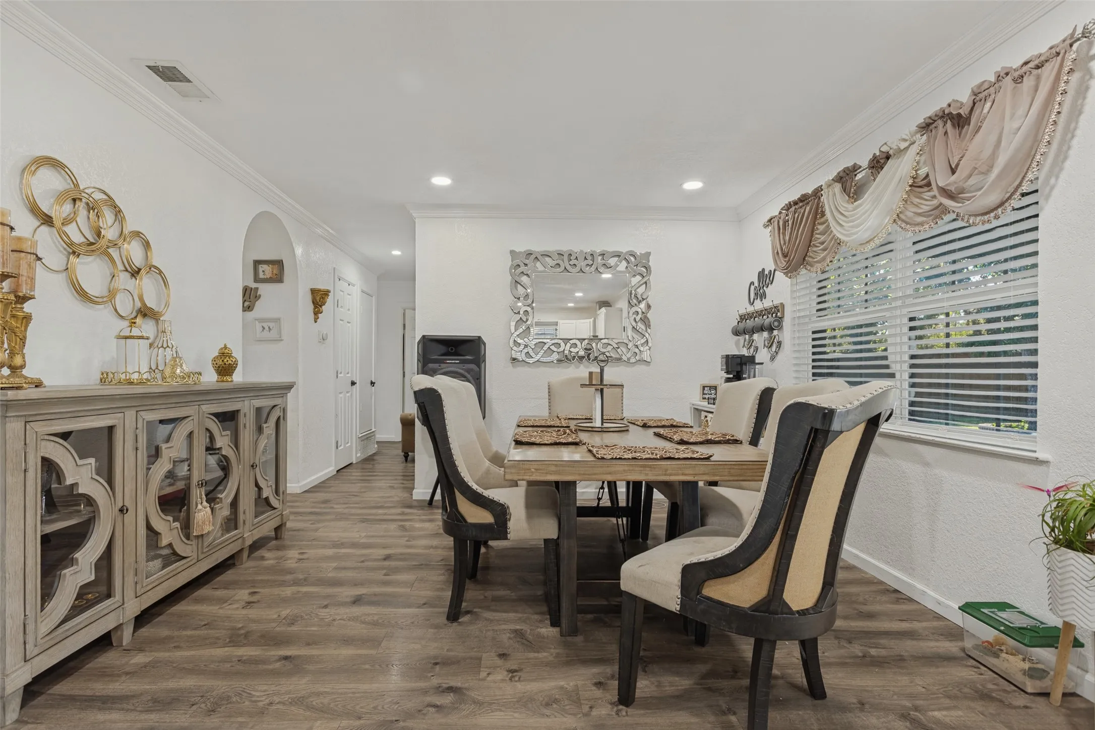 Wood-finish flooring, recessed lighting, crown molding, and an arched entry