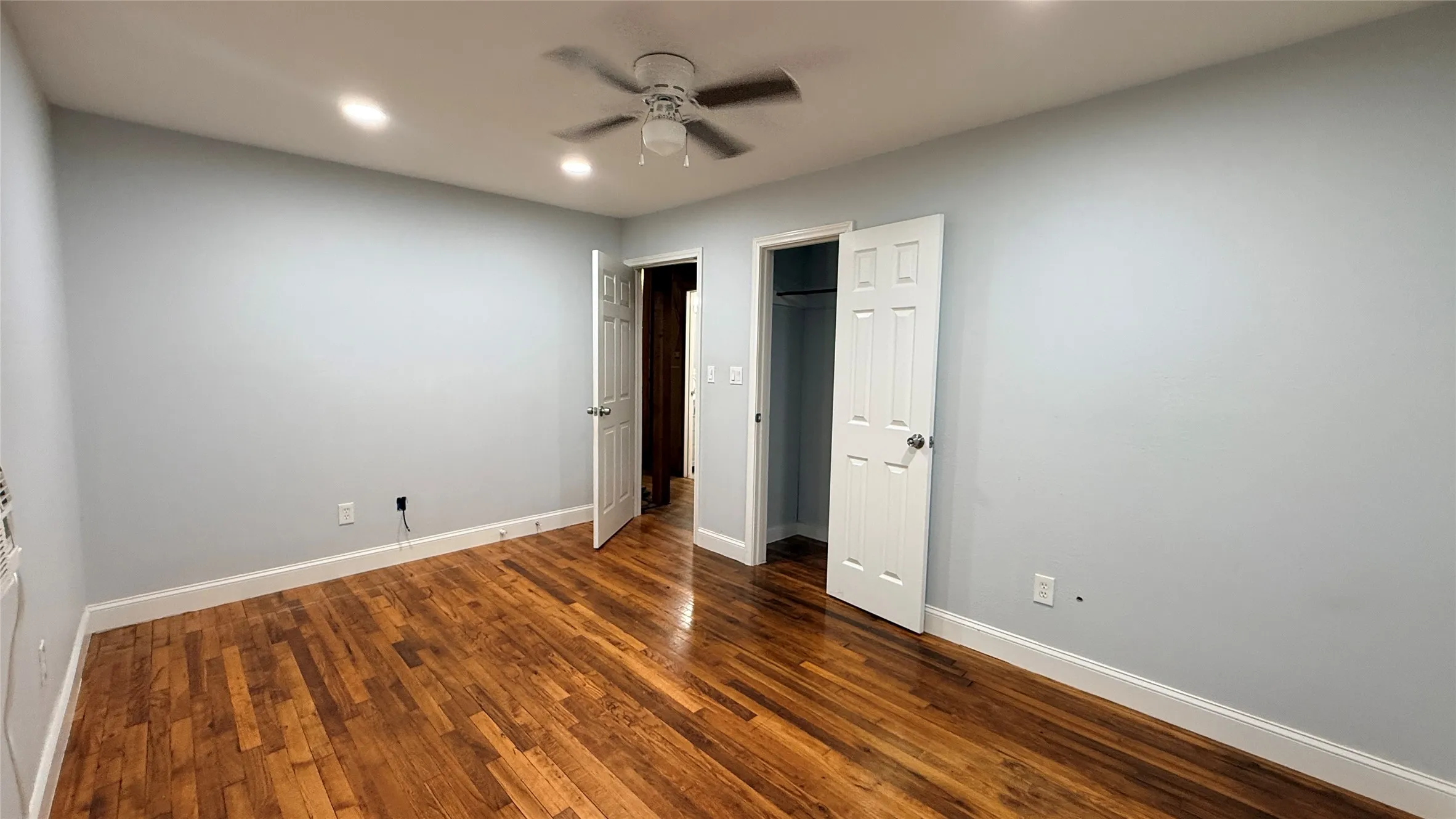 Wood-finish flooring with recessed lighting and a ceiling fan