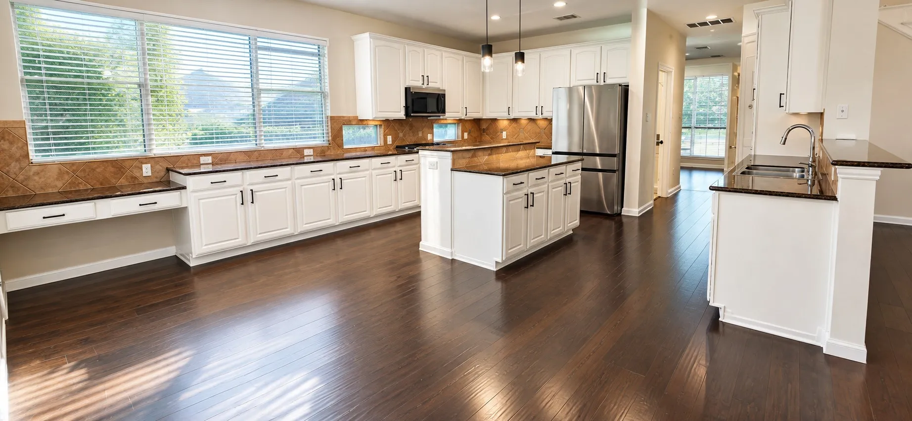 Gourmet kitchen featuring stainless steel appliances, white cabinetry, dark countertops, a tiled backsplash, and wood-finish flooring