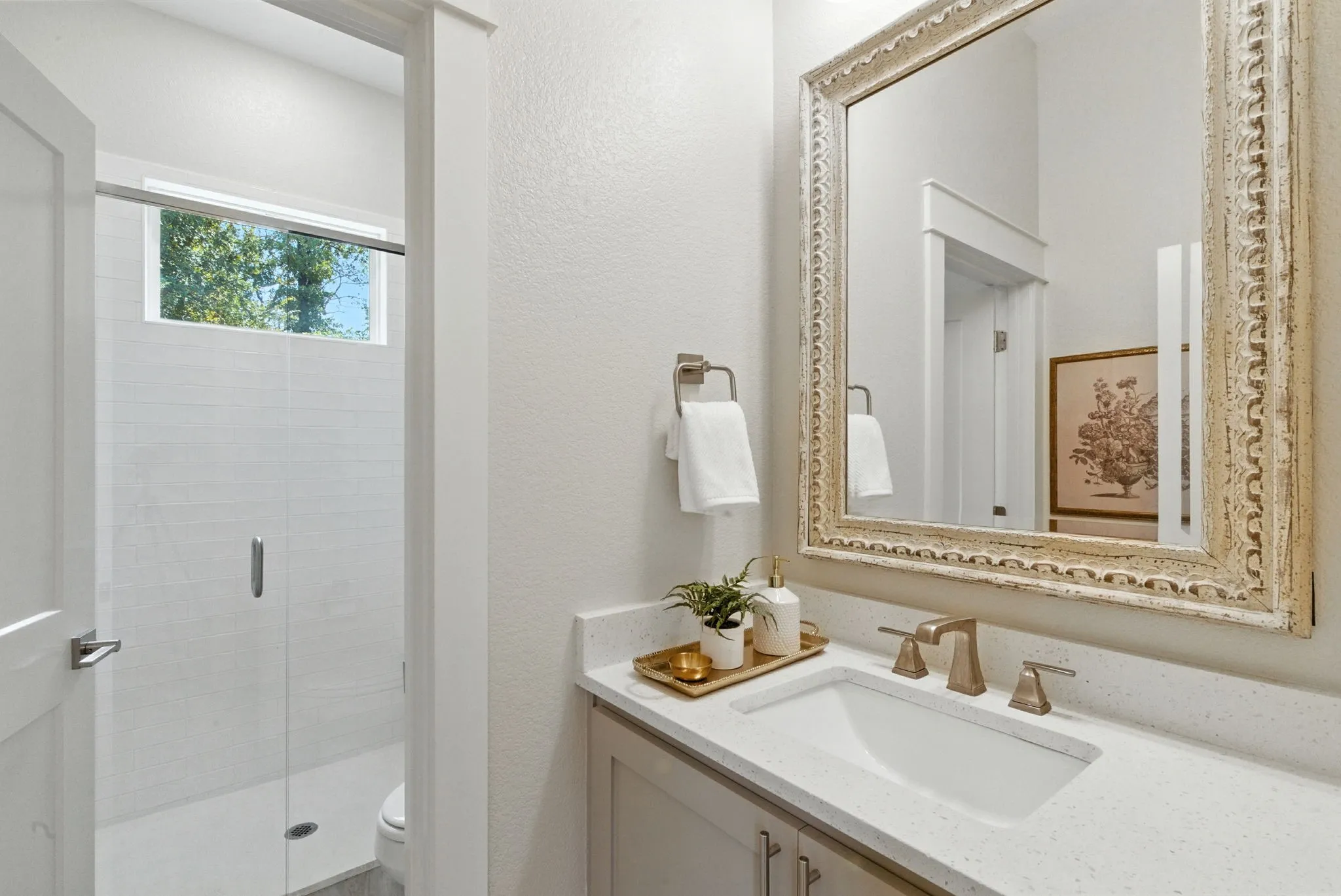 Built-in vanity with light-toned countertop, undermount sink, and brushed brass-finish faucet