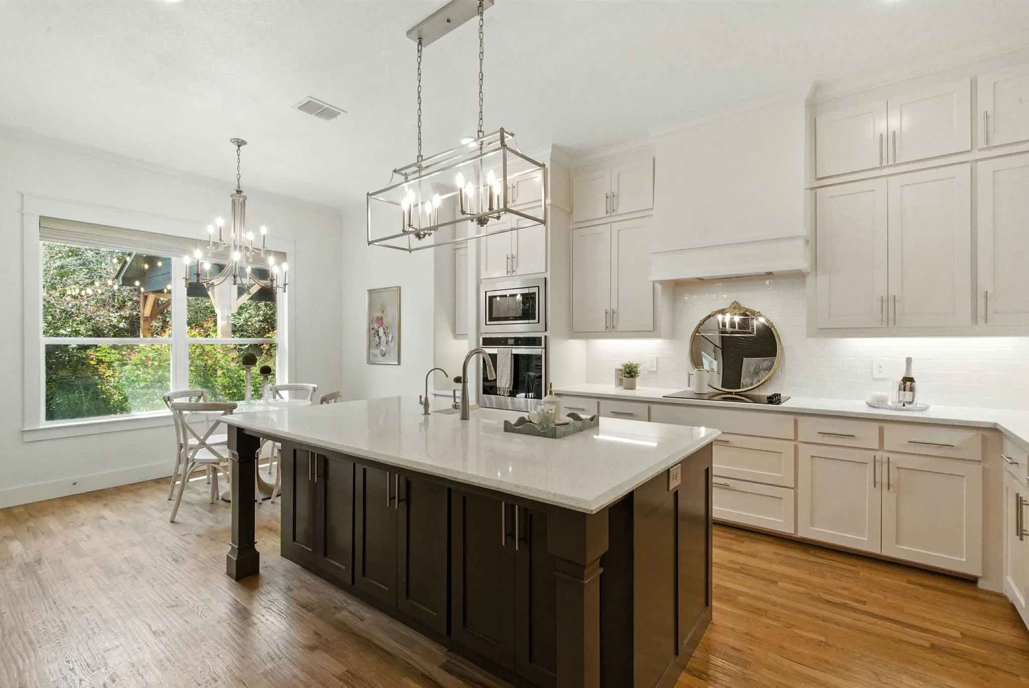 Modern kitchen featuring wood-finish flooring, white cabinetry, integrated stainless steel appliances, a center island with a light-toned countertop, and recessed lighting
