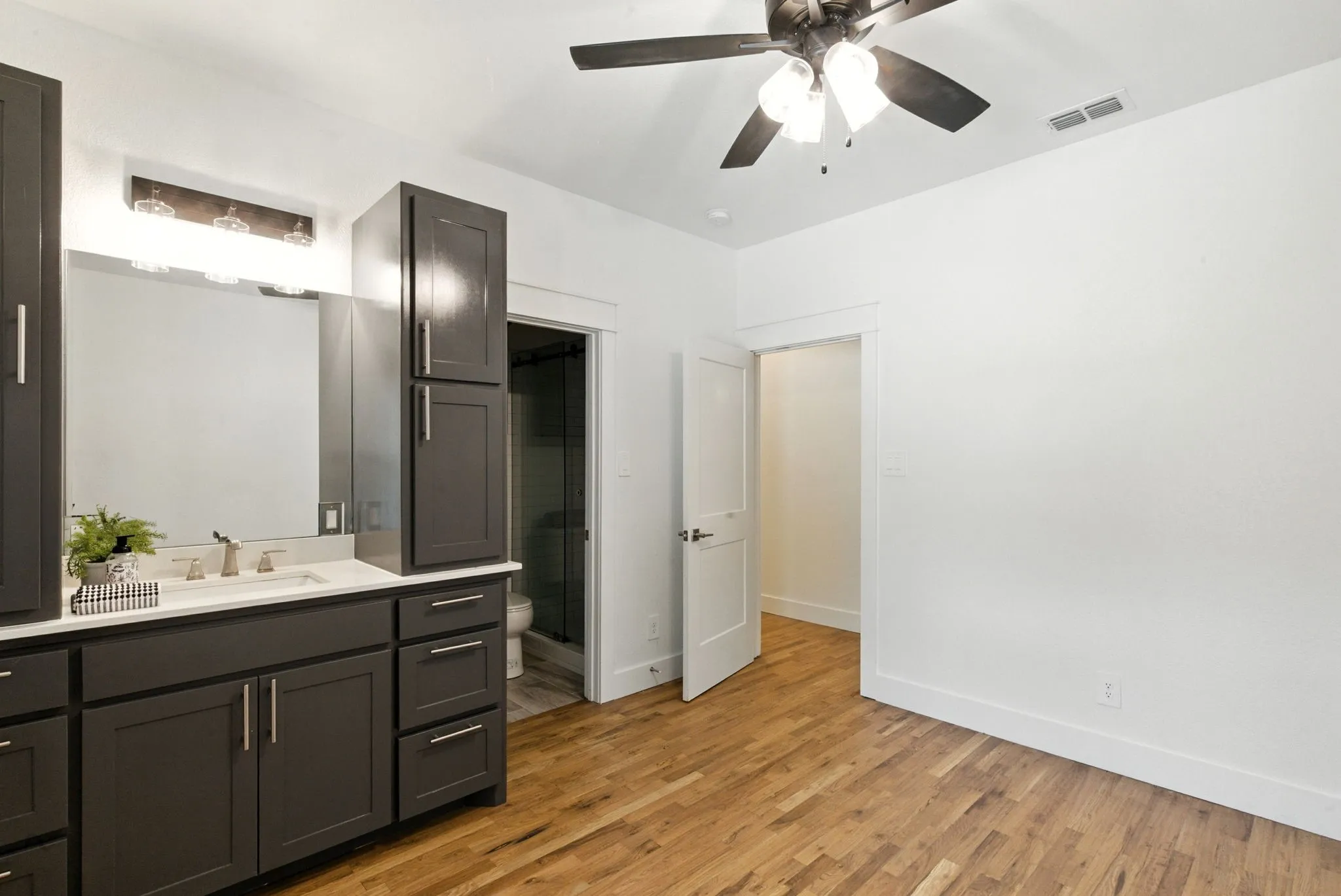 Wood-finish flooring with a vanity featuring dark cabinetry and a light-colored countertop