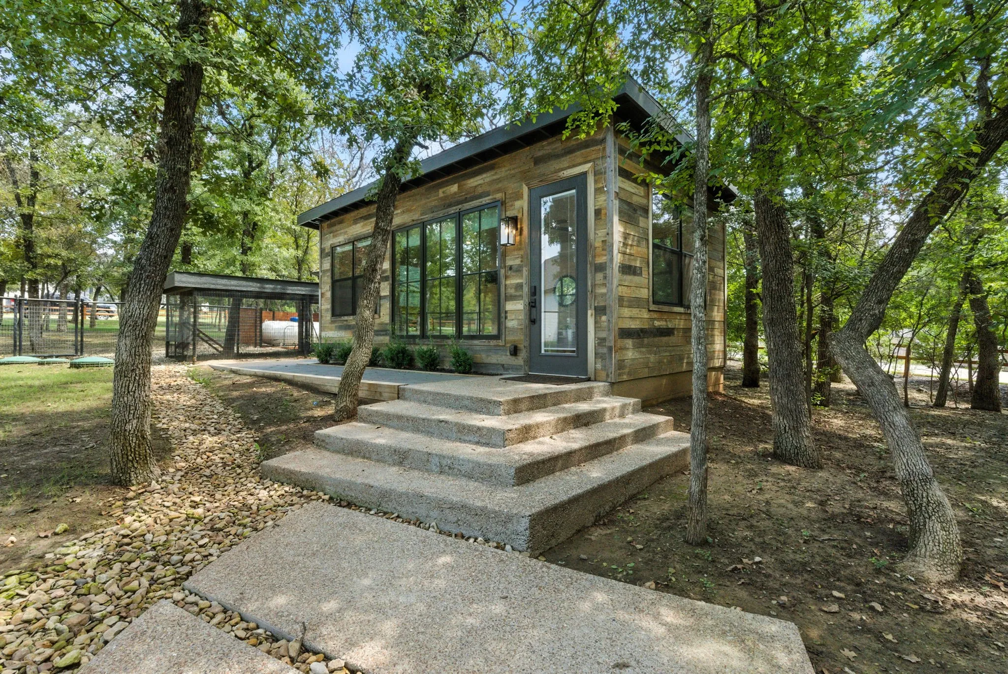 Wood-finish exterior with dark trim windows, concrete steps, and a concrete pathway