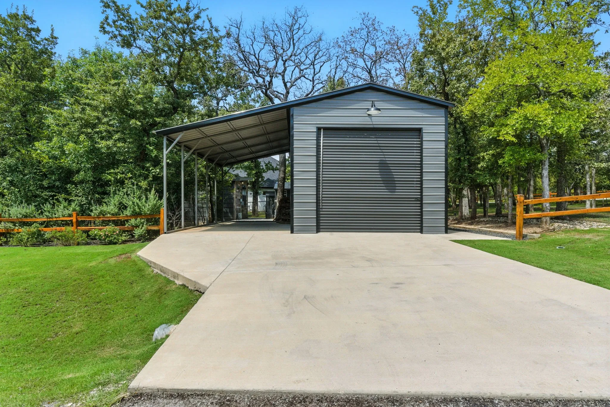 Detached metal garage with a roll-up door, an attached covered carport, and a concrete driveway