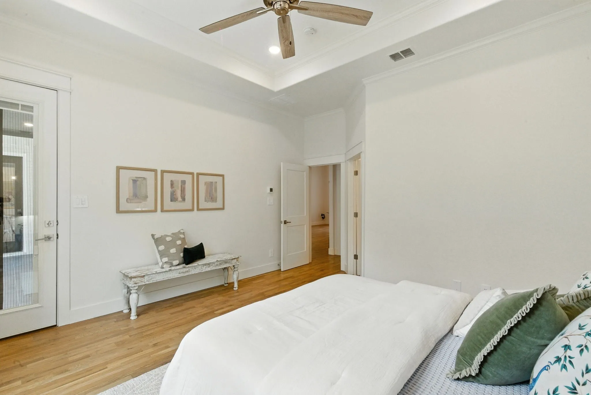 Recessed lighting, crown molding, tray ceiling, wood-finish flooring, and a glass-paneled door