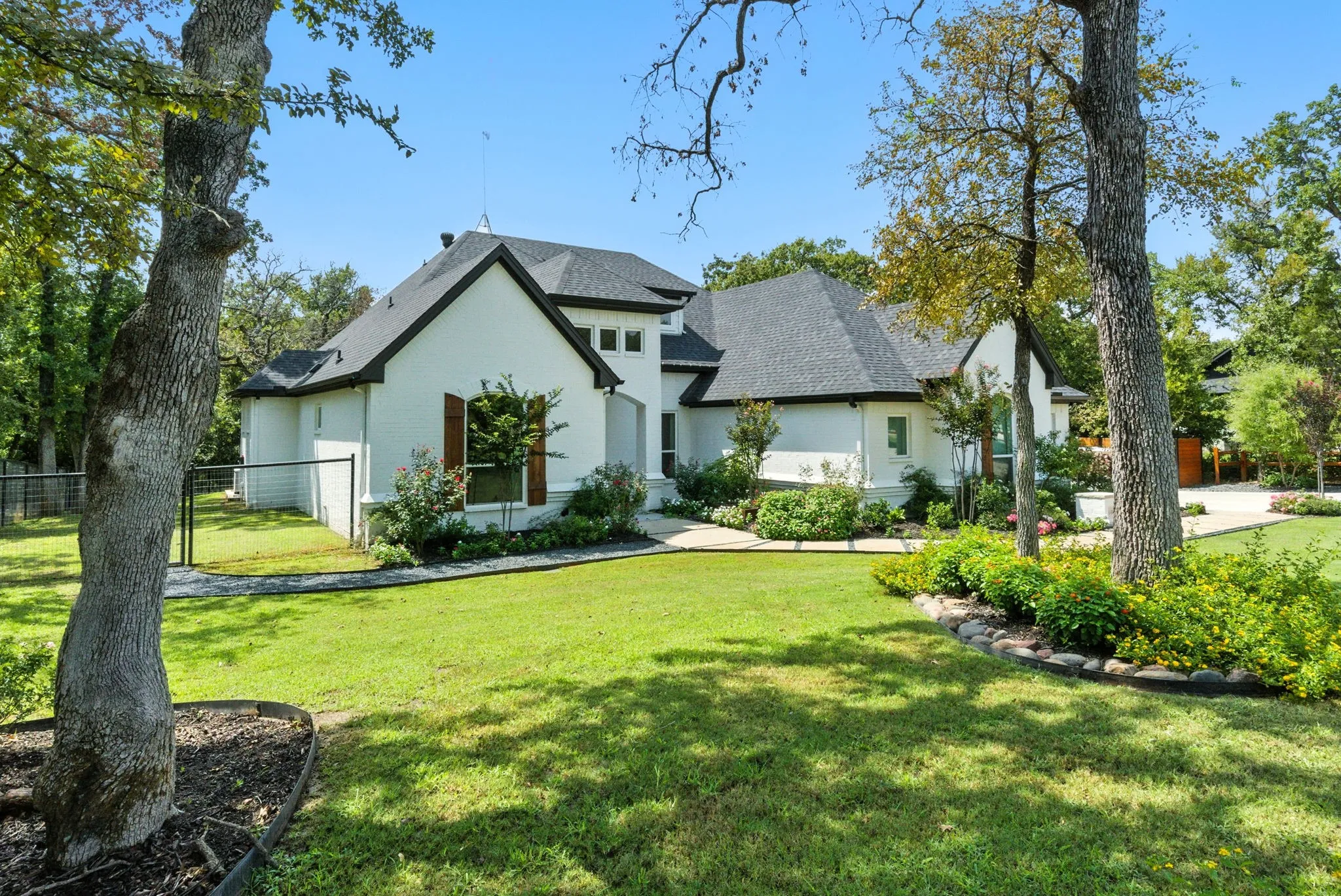 White brick exterior with dark trim and a dark shingle roof