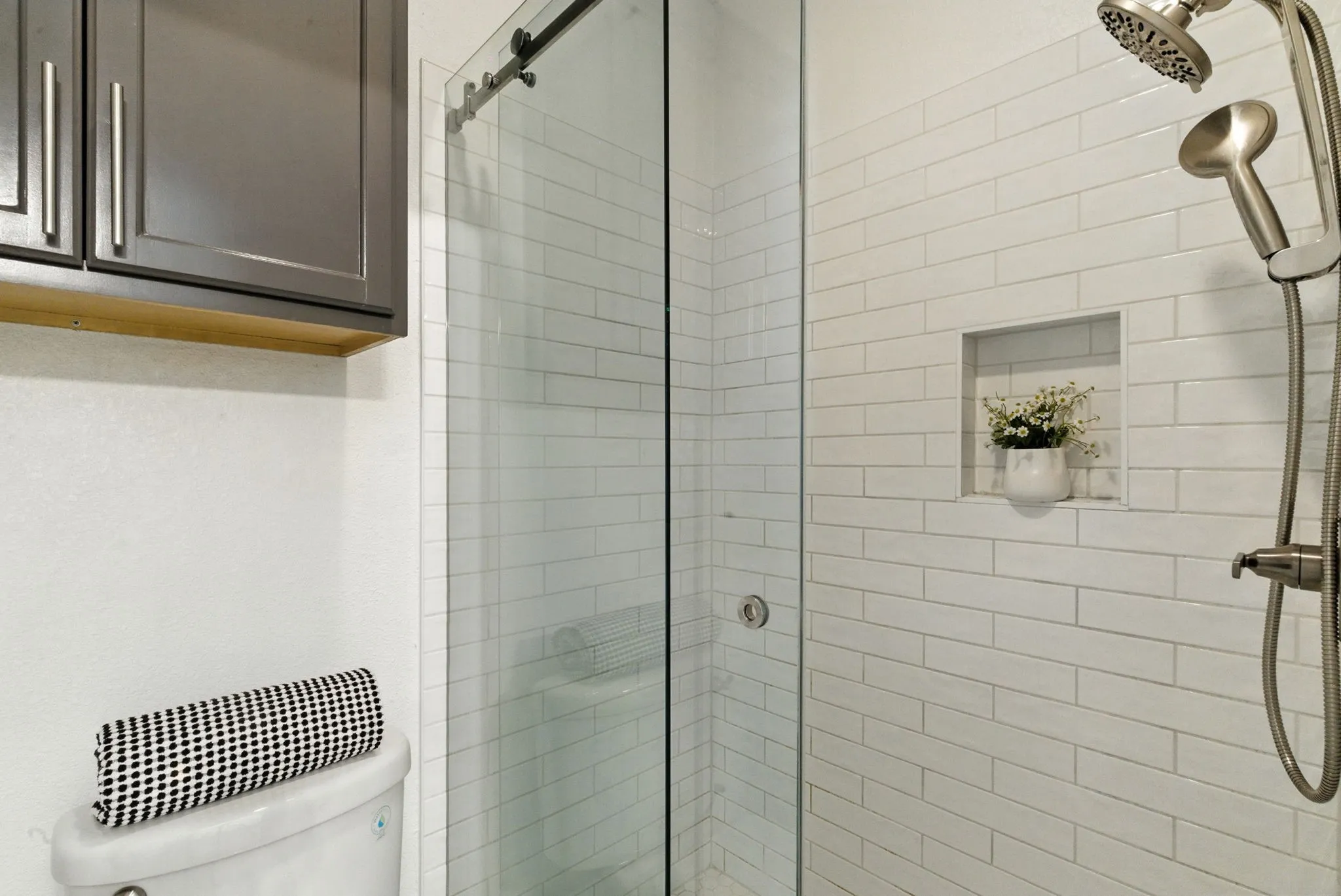Glass-enclosed shower with white subway tile, brushed nickel shower fixtures, and an integrated shower niche