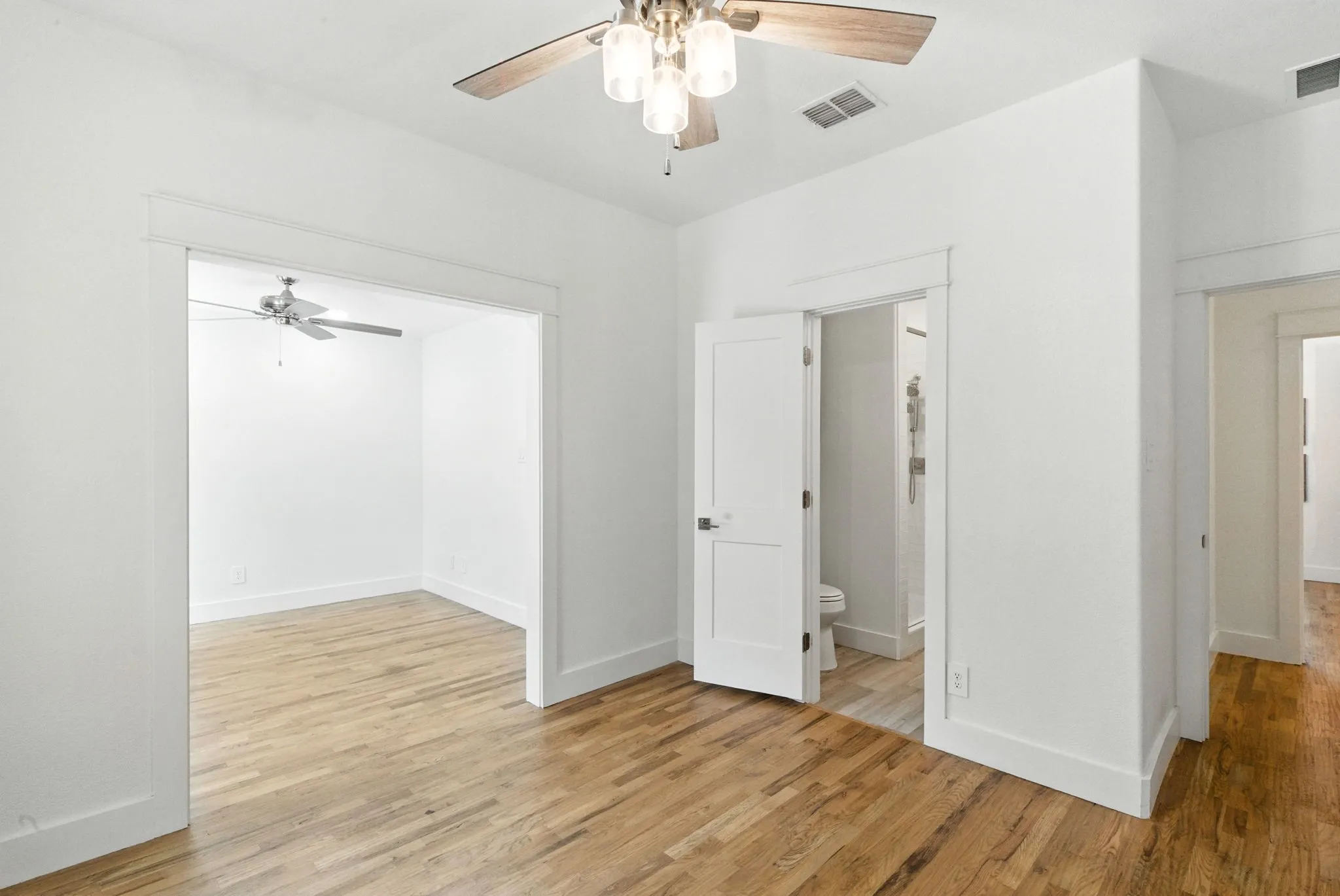 Wood-finish flooring throughout, bright white walls, and a recessed doorway