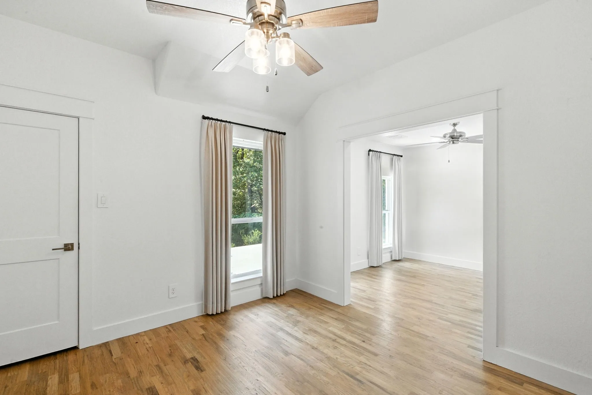 Wood-finish flooring throughout, bright white walls, and a contemporary ceiling fan with integrated lighting