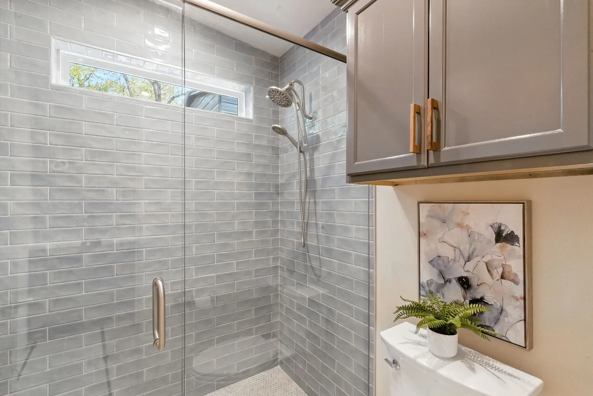 Glass-enclosed shower with subway tile surround, integrated shower bench, and transom window