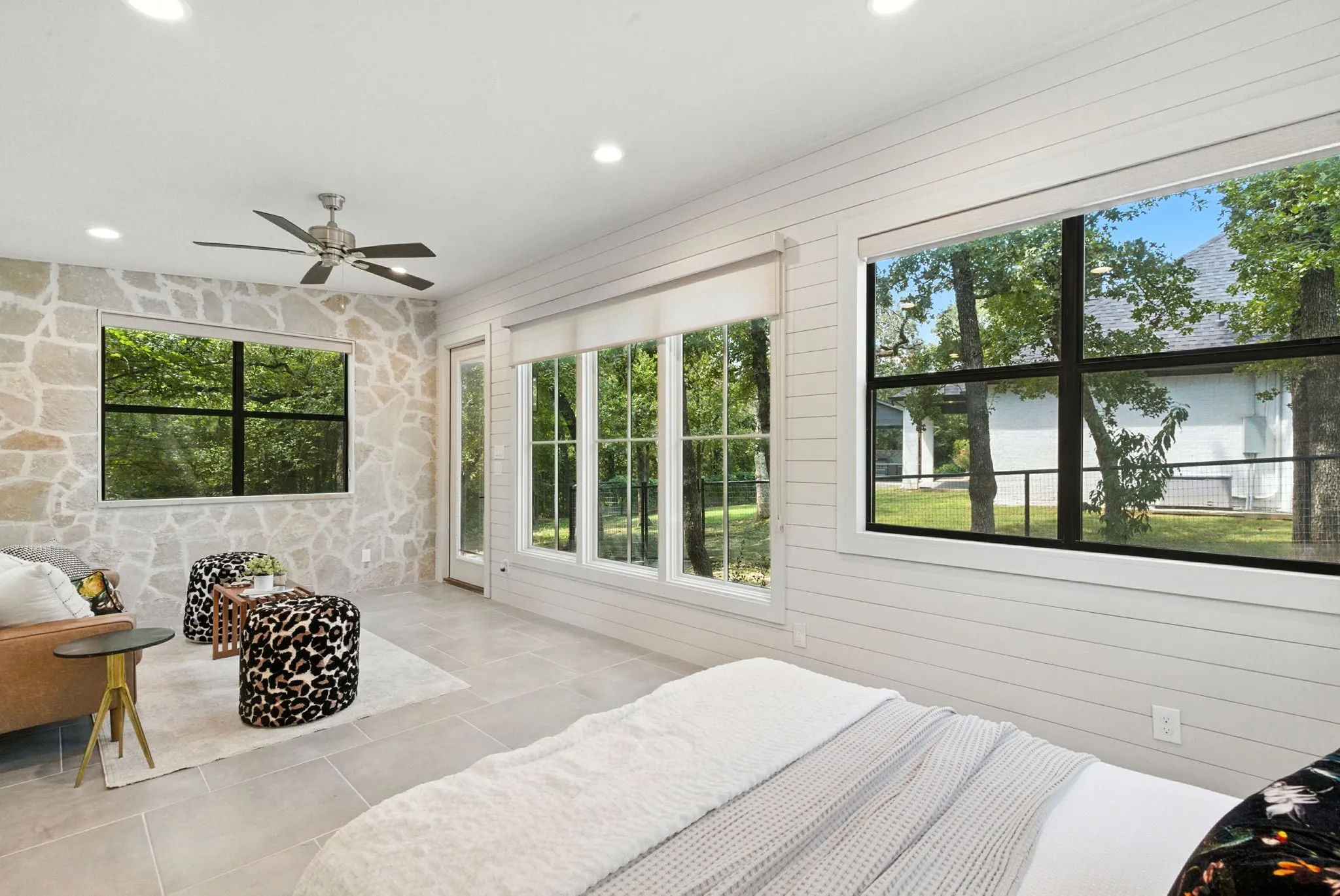 Recessed lighting, ceiling fan, natural stone accent wall, shiplap wall finish, and large windows with black frames