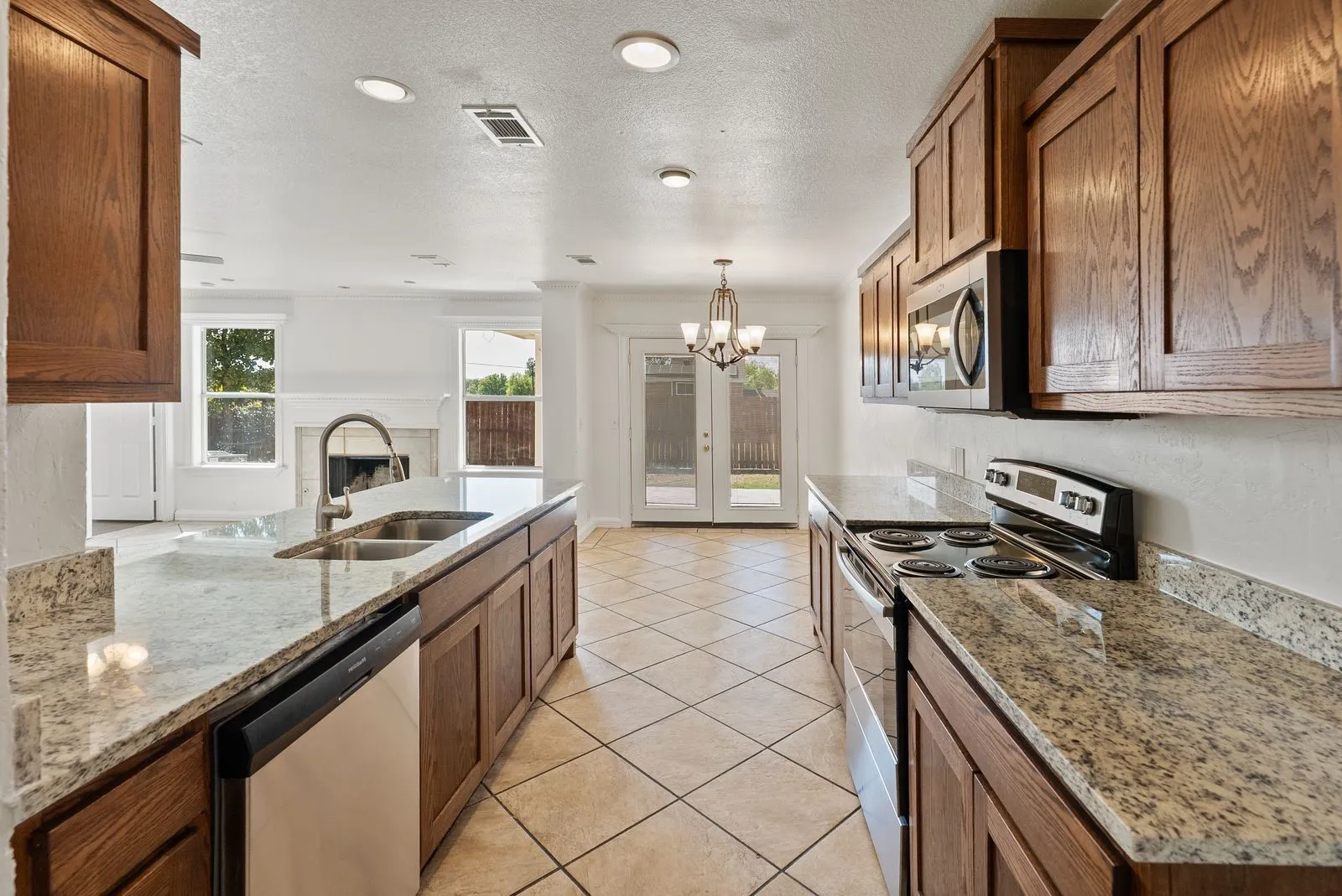 Kitchen featuring a double basin sink, stainless steel appliances, granite countertops, wood cabinetry, and recessed lighting