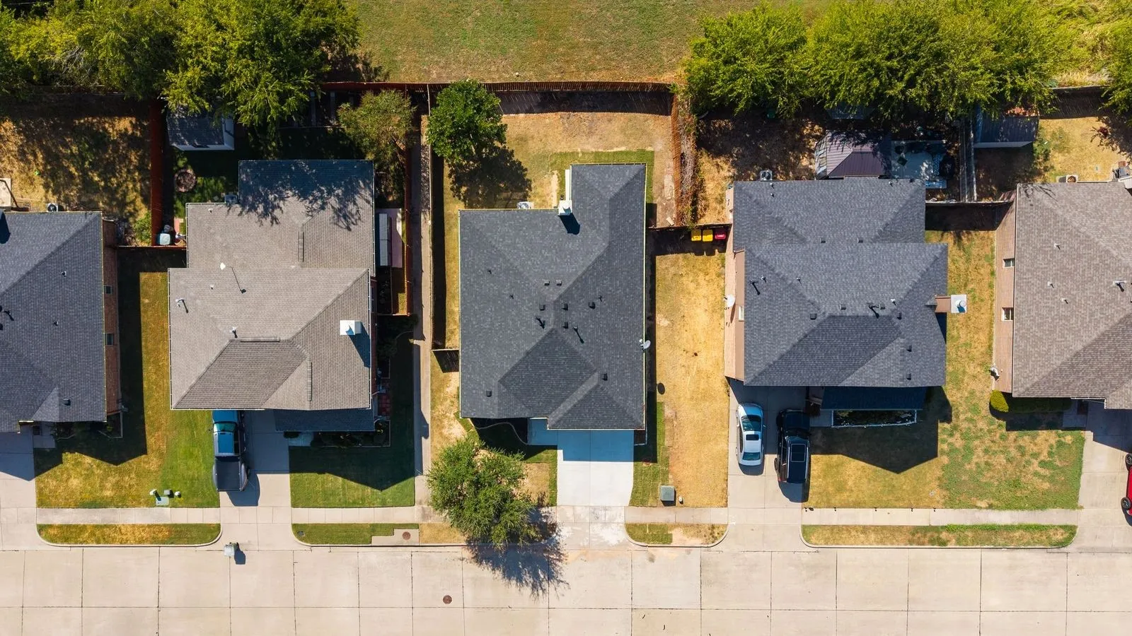 Residential property with a dark shingled roof, a paved driveway, and a partially grassed yard