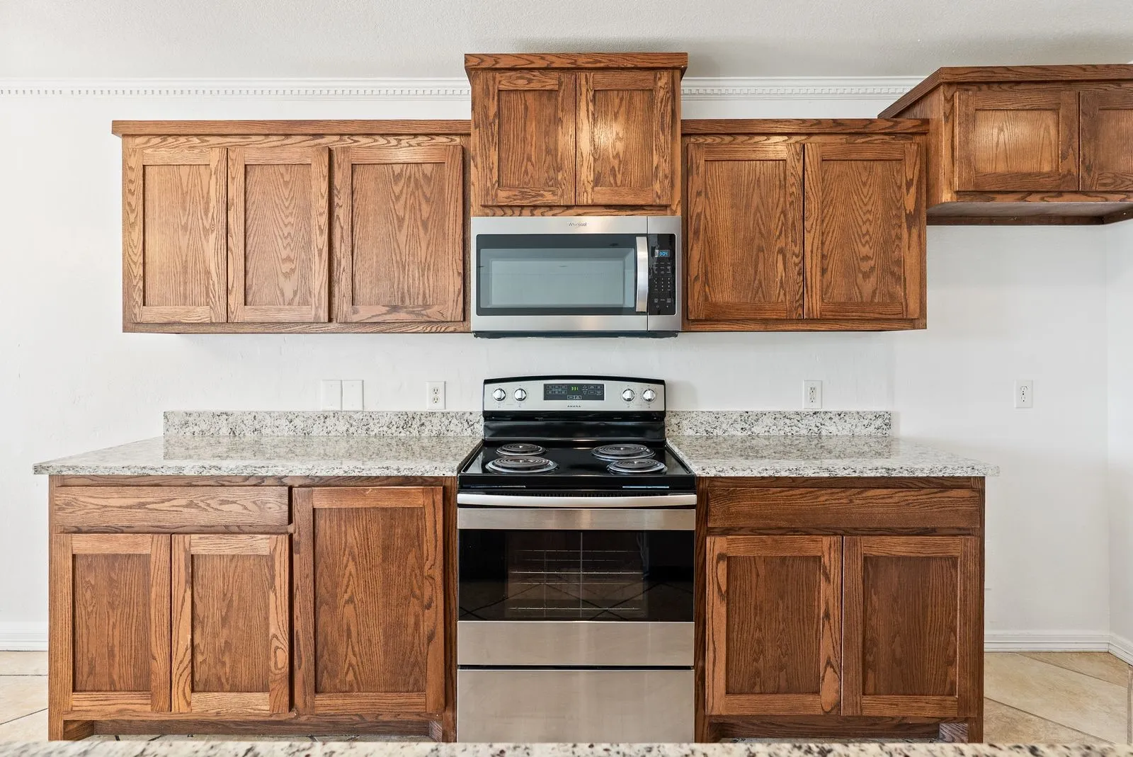 Wood-finish cabinetry paired with light-toned countertops and stainless steel appliances
