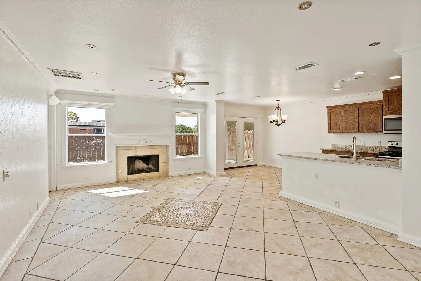 Spacious living area featuring tile flooring, a fireplace with a stone surround, and crown molding