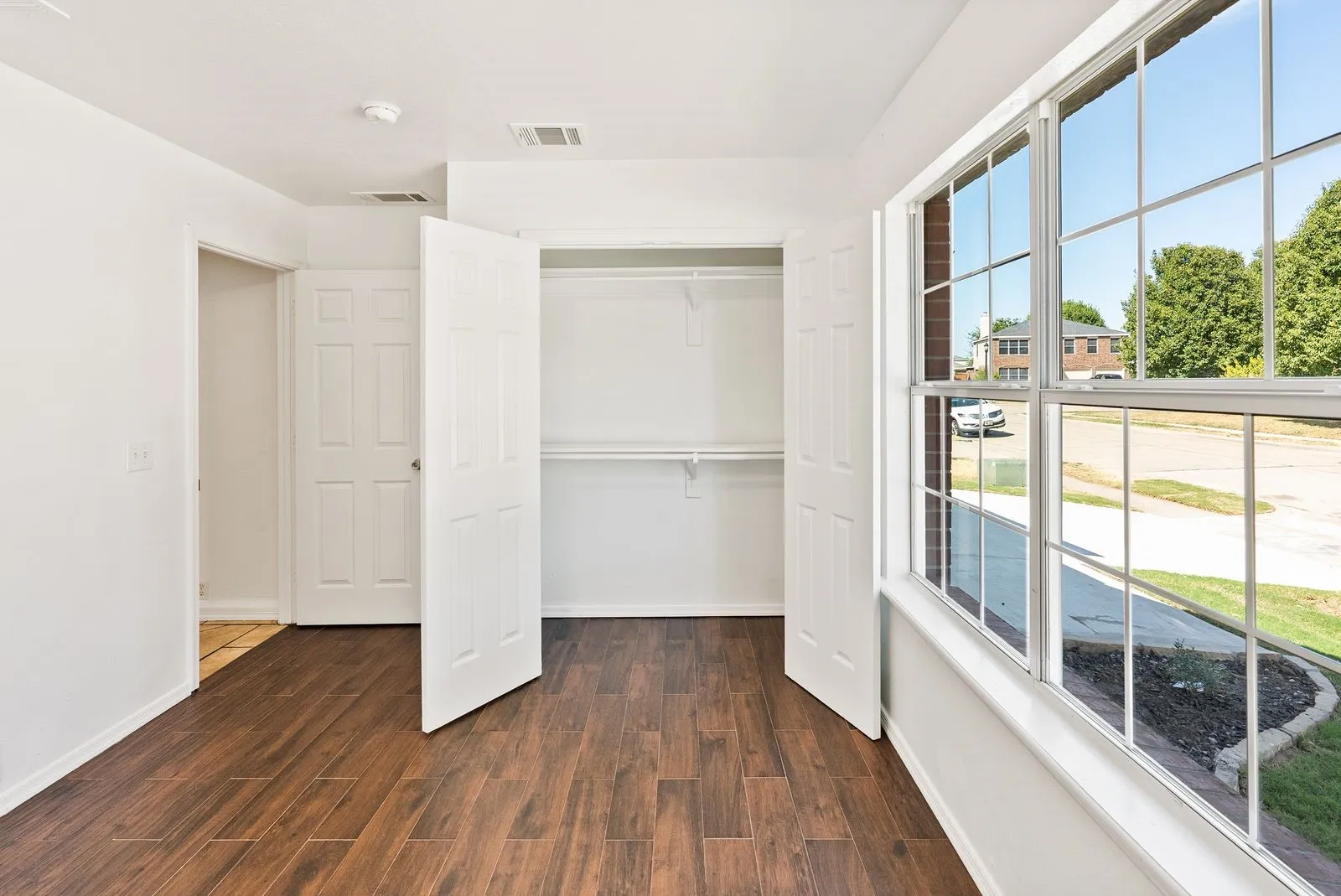 Wood-finish flooring, white walls, and a large multi-pane window