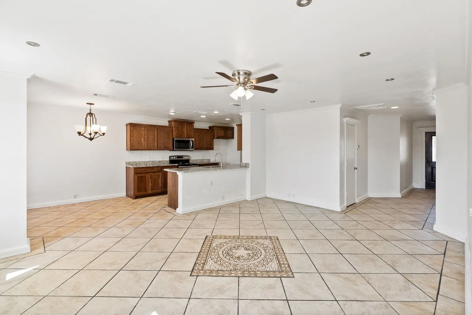 Open-concept layout featuring a kitchen with wood cabinetry and stone-look countertops, tile flooring throughout, recessed lighting, and a ceiling fan