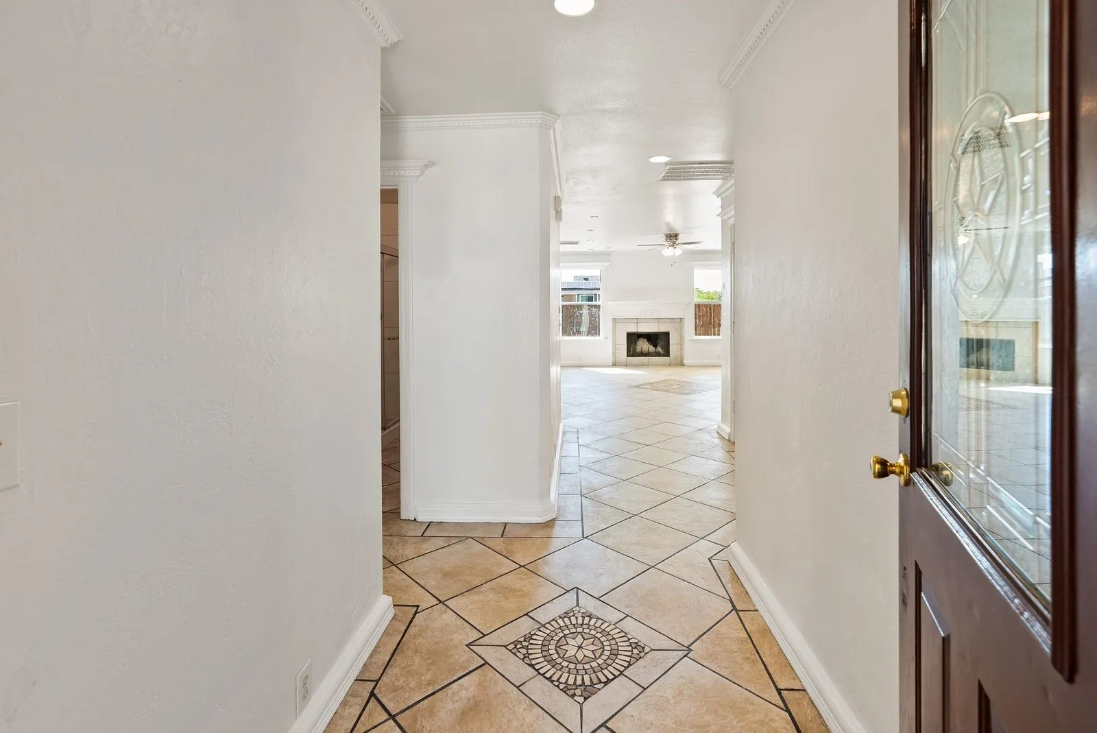 Entryway featuring decorative tile flooring, crown molding, and a front door with an ornate glass insert