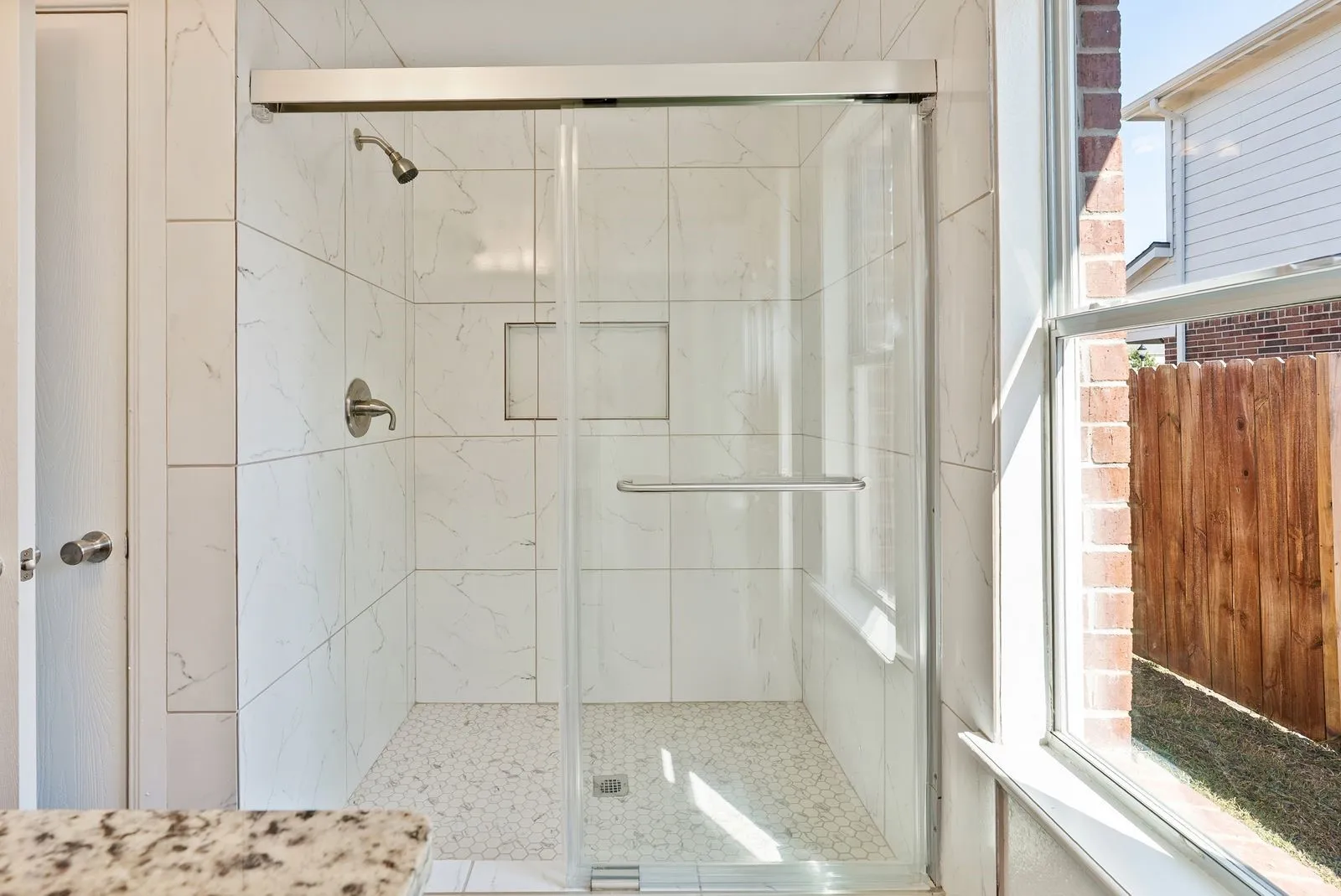 Walk-in shower with clear glass enclosure and brushed nickel fixtures