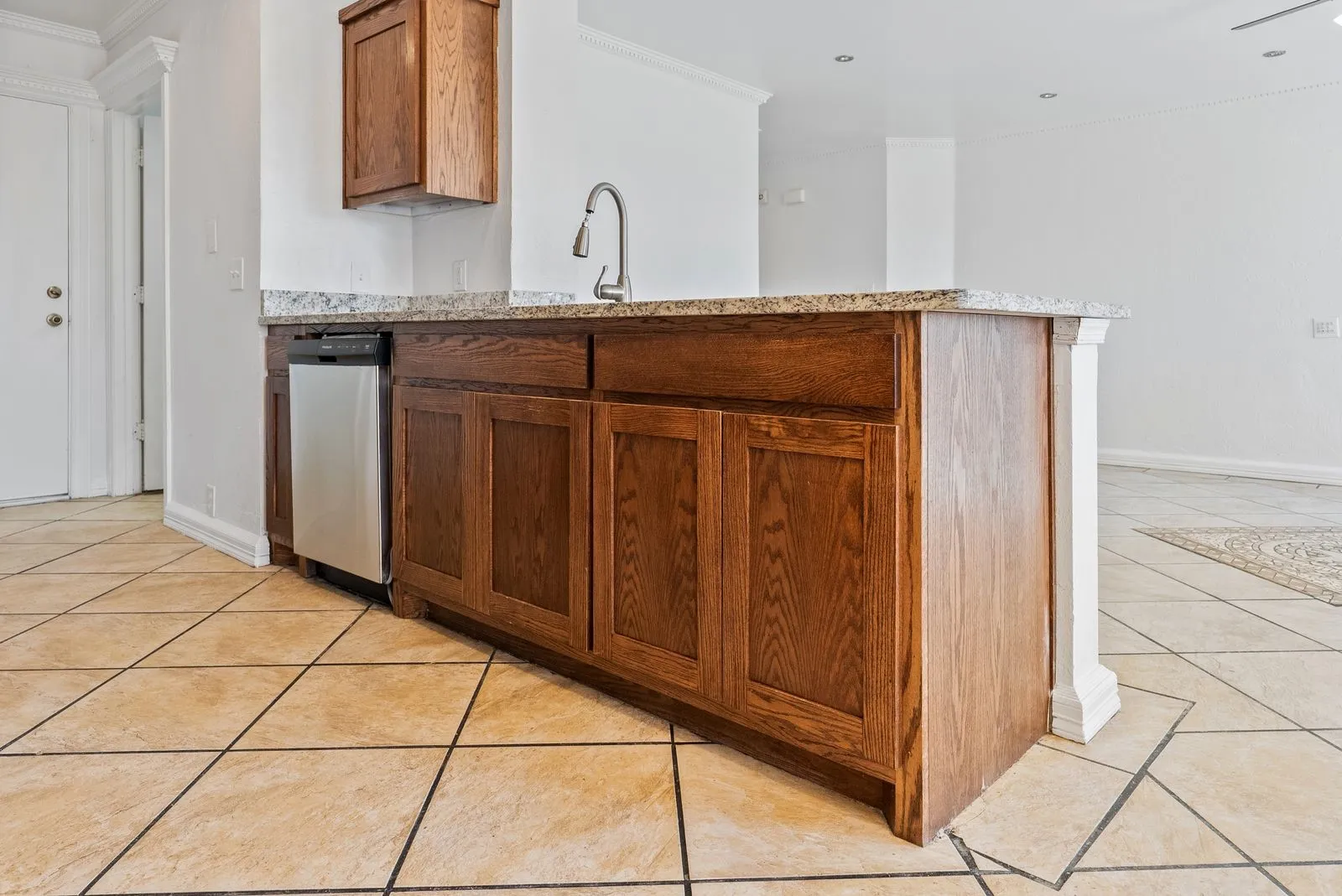 Wood cabinetry with a granite-style countertop, stainless steel dishwasher, and a gooseneck faucet