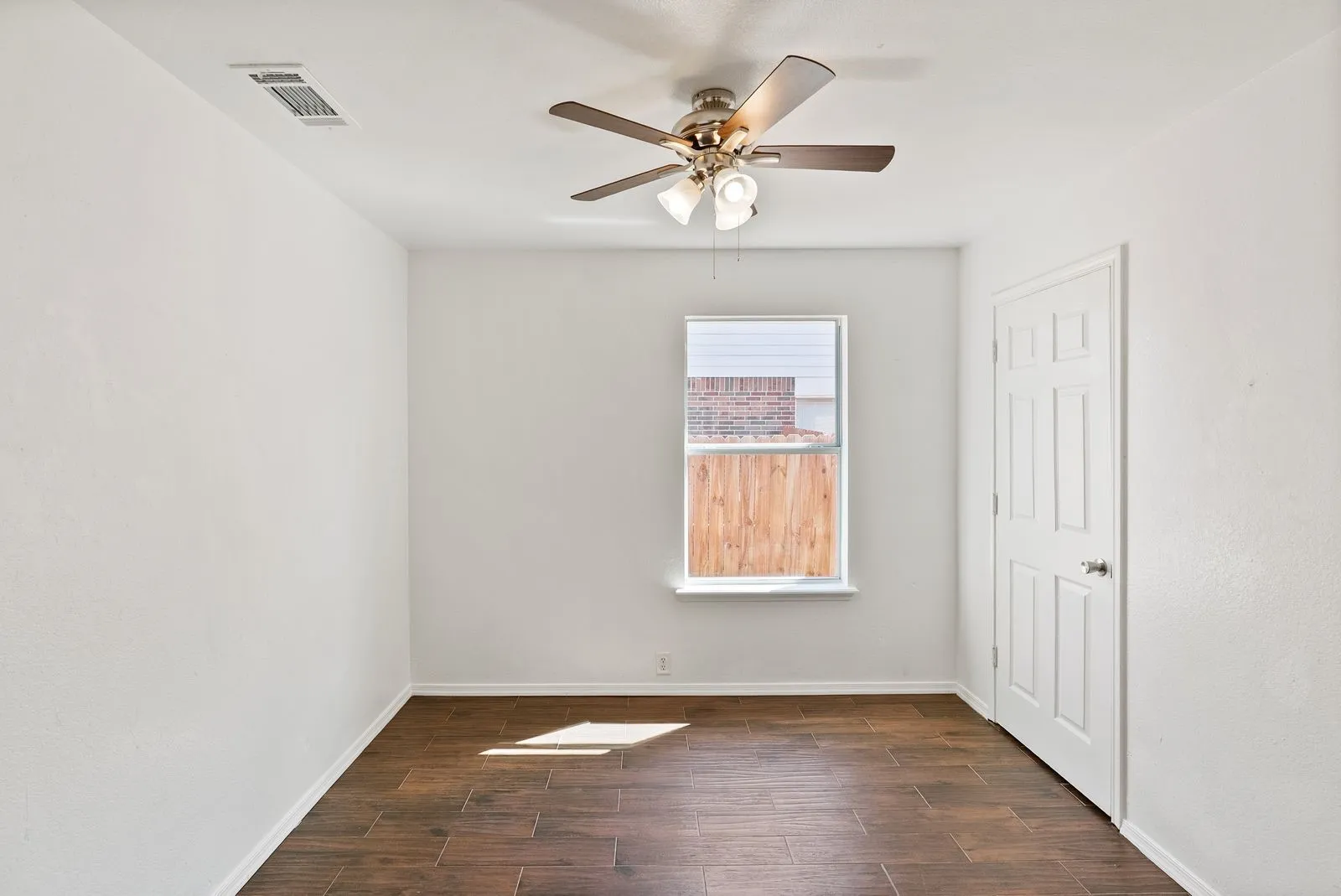 Room featuring wood-look tile flooring, a window, a paneled door, and a ceiling fan with integrated lighting