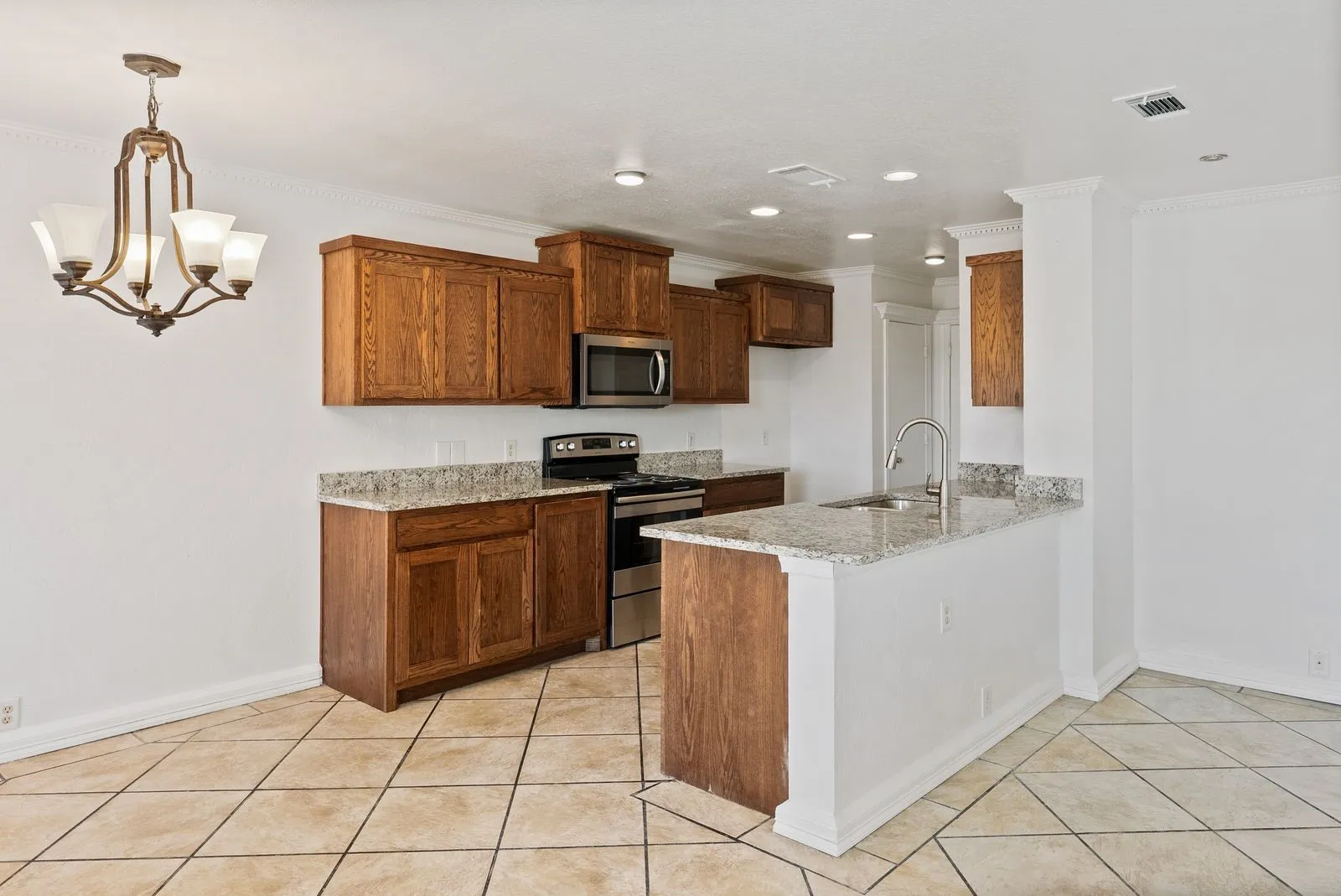 Kitchen featuring wood cabinetry, stainless steel appliances, granite countertops, and tiled flooring