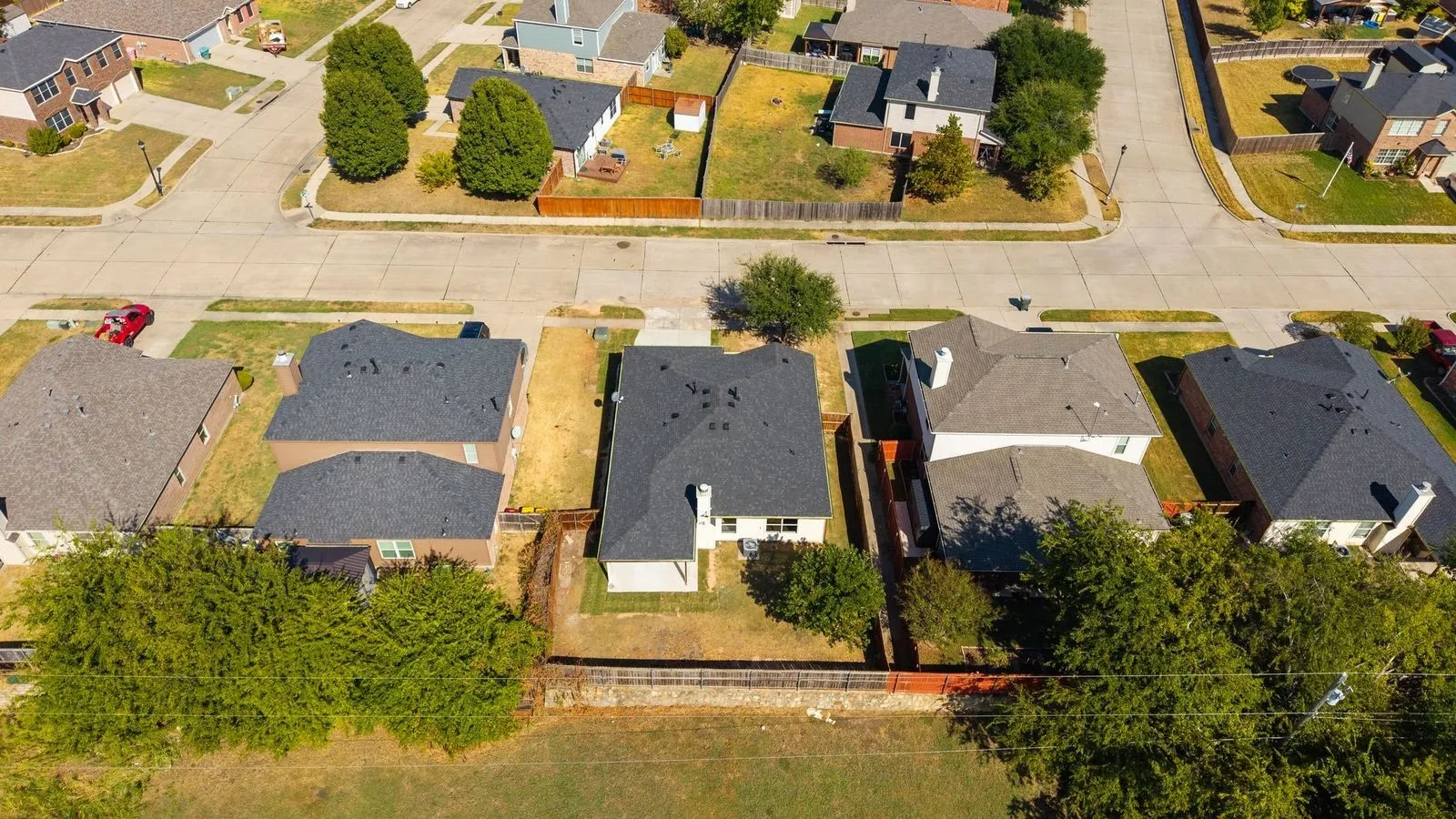 Residential property with dark shingle roofing, surrounded by established neighborhood infrastructure and mature trees