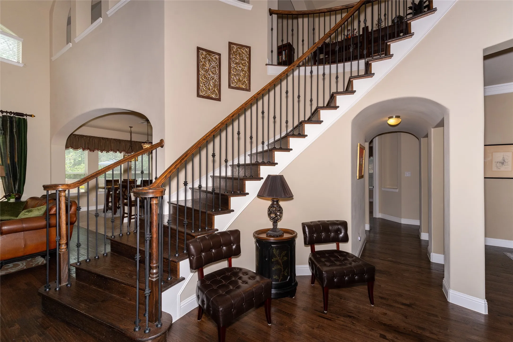 Sweeping staircase with dark wood-finish treads and wrought iron balusters