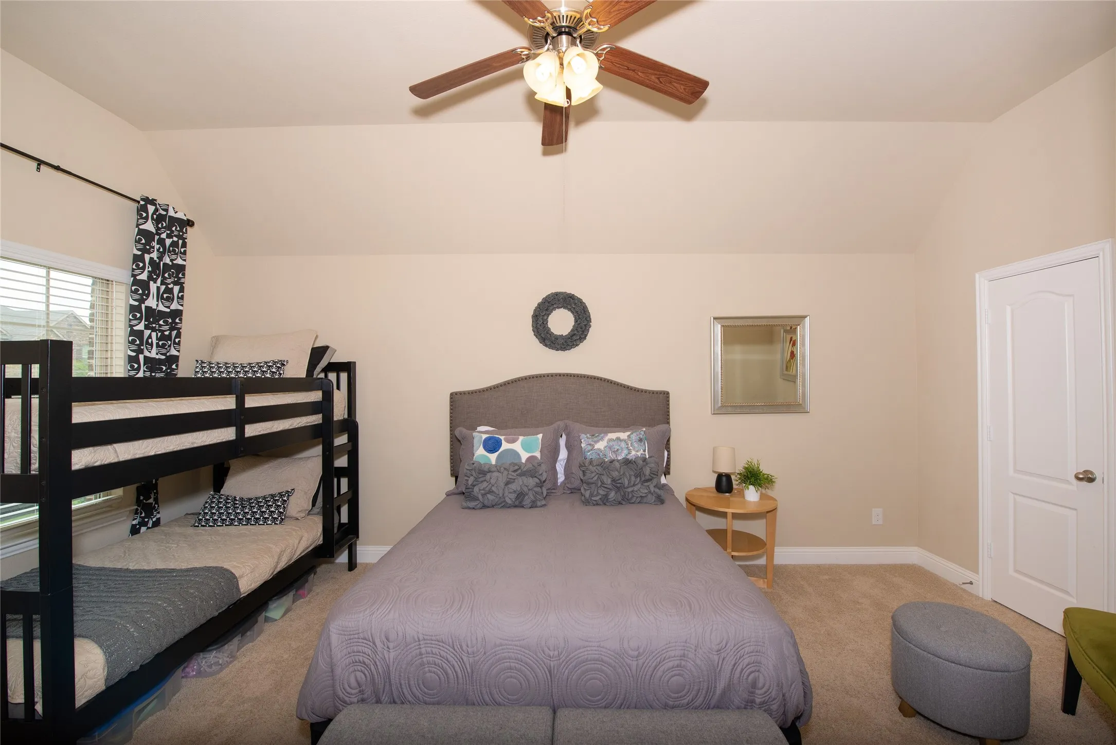 Vaulted ceiling bedroom with a ceiling fan, carpeted flooring, and an interior panel door