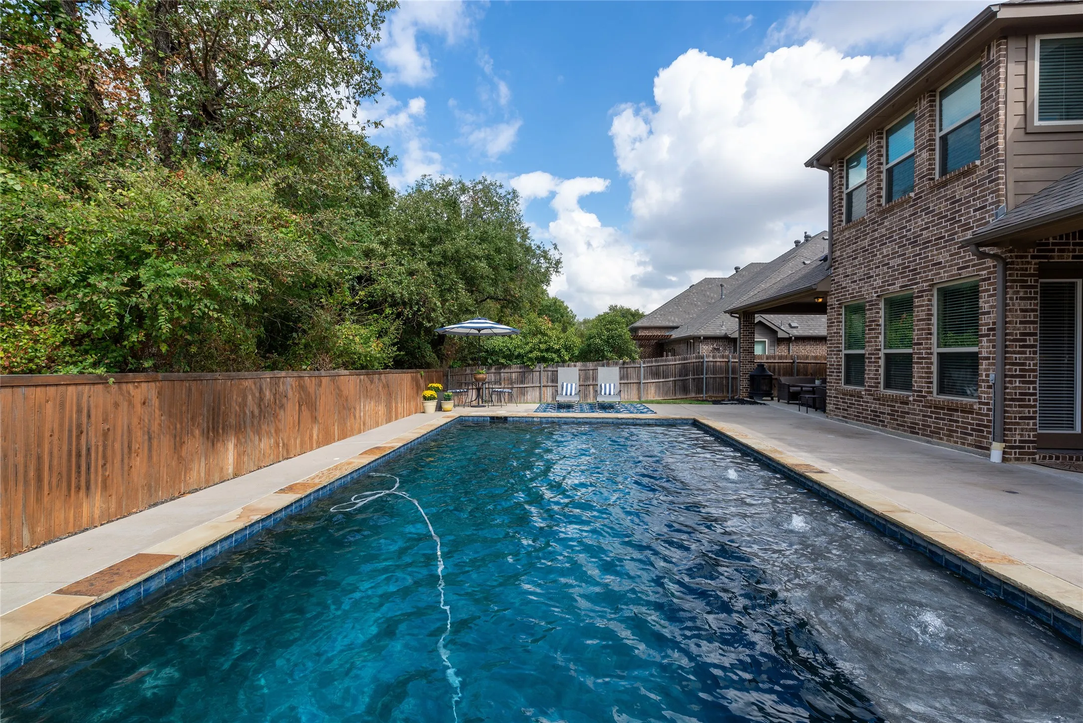 Resort-style swimming pool featuring crystal-blue water, integrated spa jet, and surrounding concrete decking
