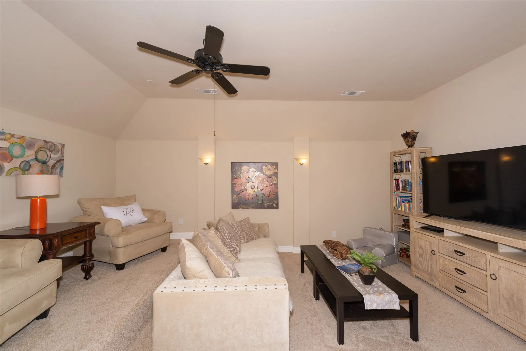 Carpeted room with vaulted ceiling and a ceiling fan