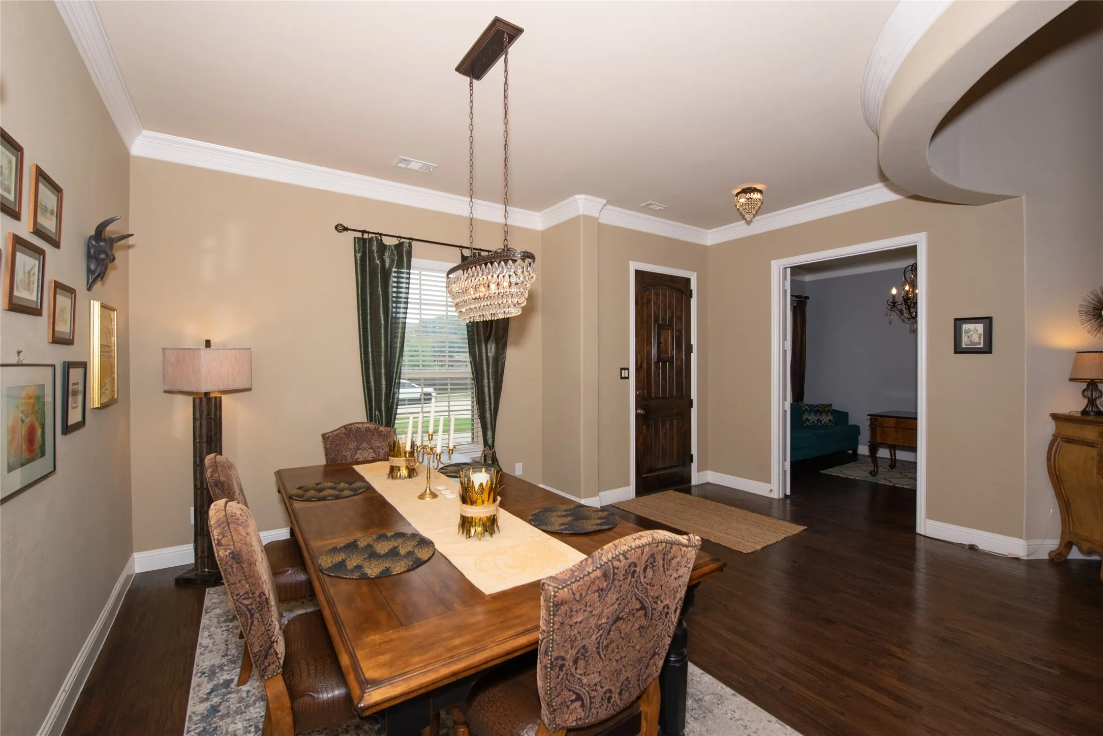 Dark wood-finish flooring, crown molding, and a decorative chandelier