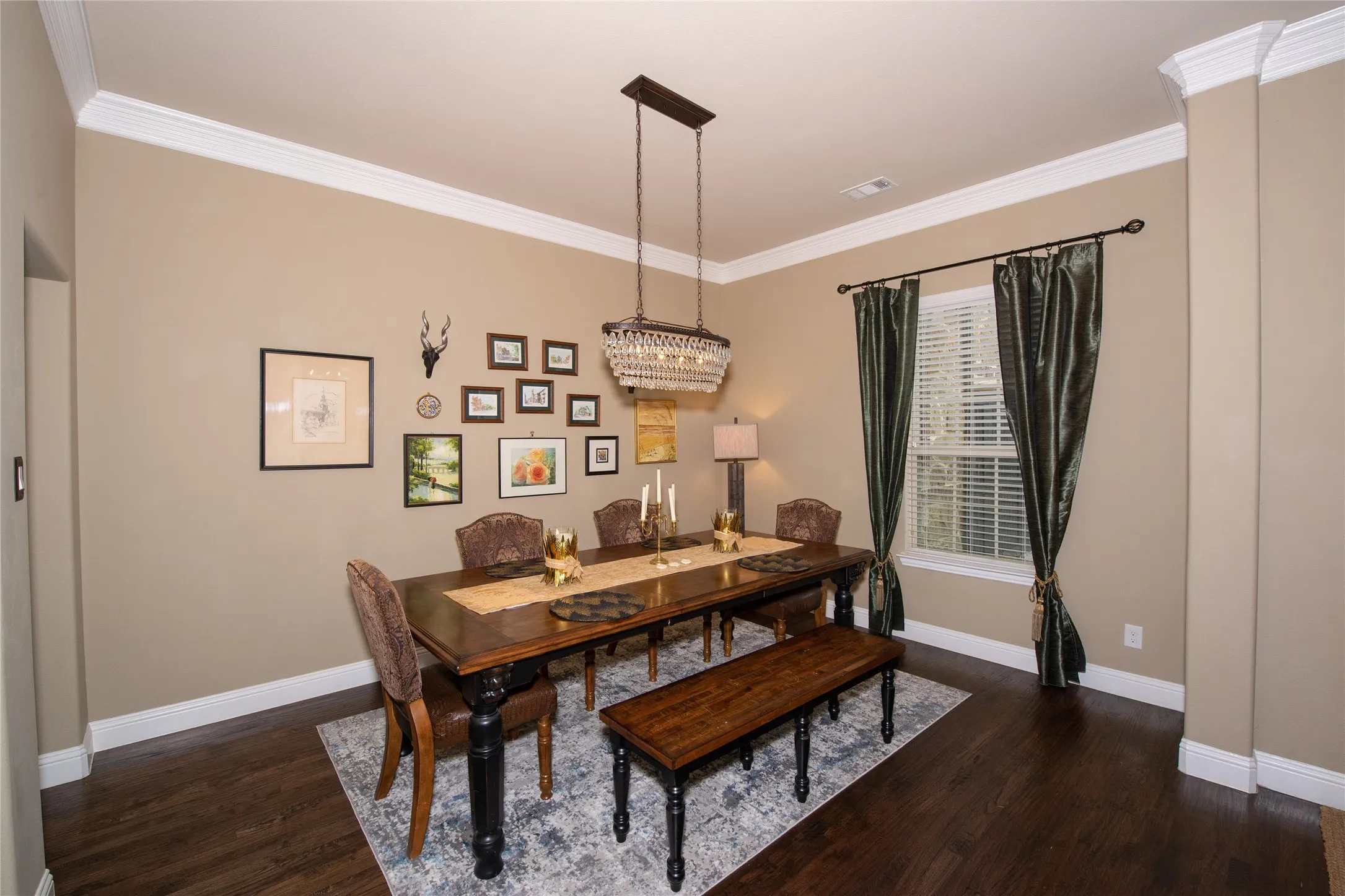 Formal dining area featuring rich wood-finish flooring, crown molding, and a chandelier