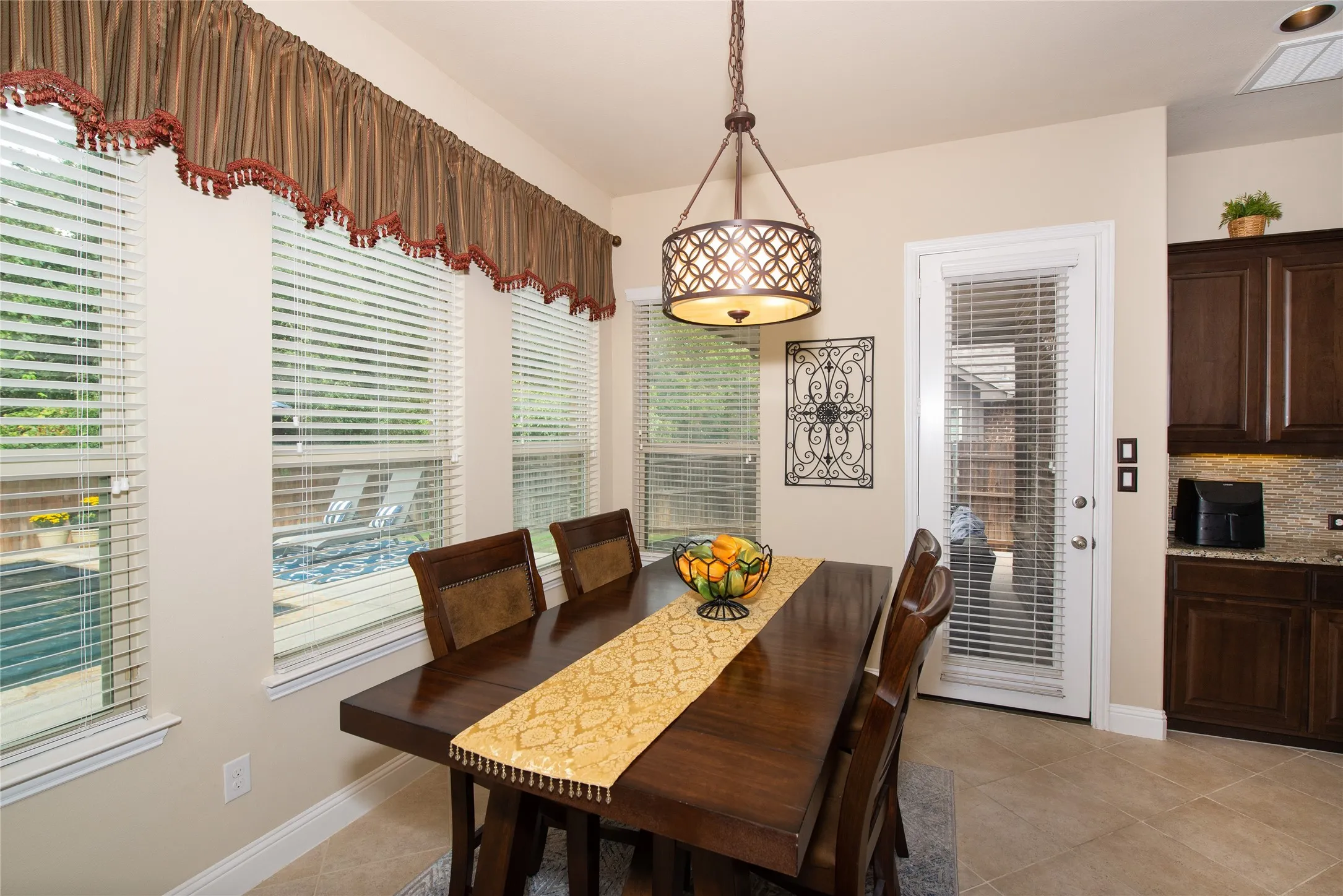Dining area featuring a dark wood finish table, tile flooring, and multiple windows with blinds