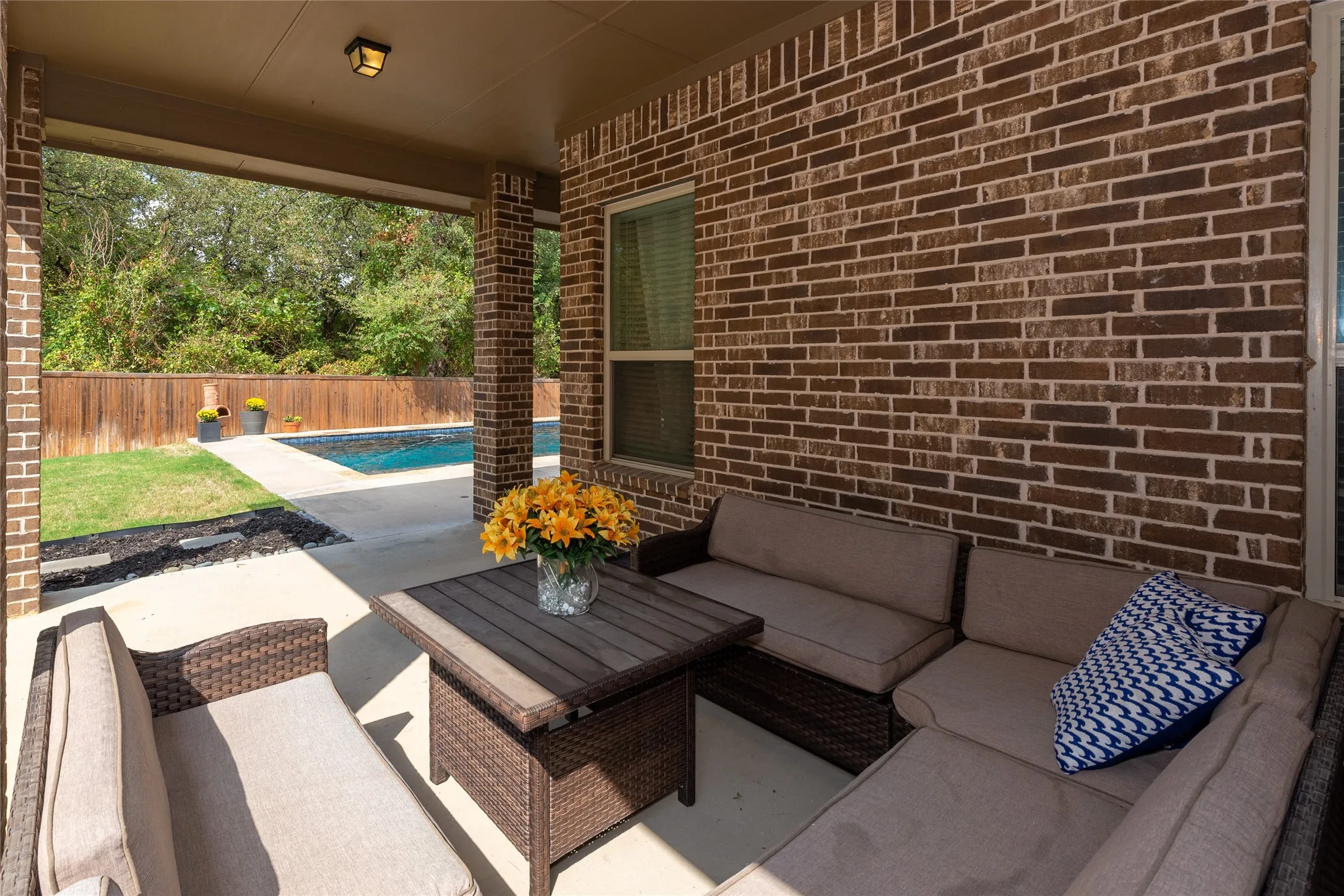 Covered patio featuring brick columns, a mounted light fixture, and a concrete floor