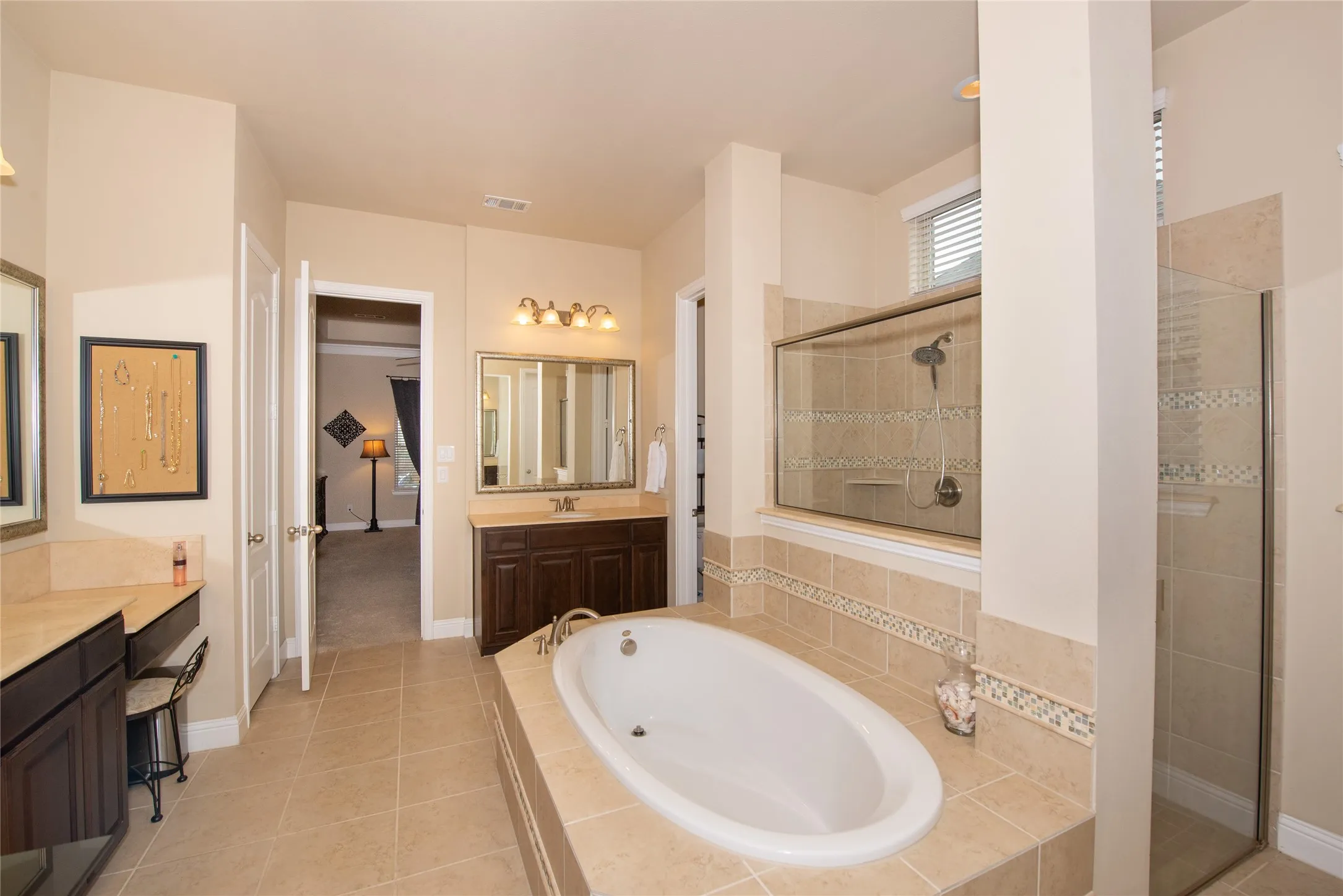 Dual vanity sinks with wood cabinetry, a built-in soaking tub, and a separate glass-enclosed shower