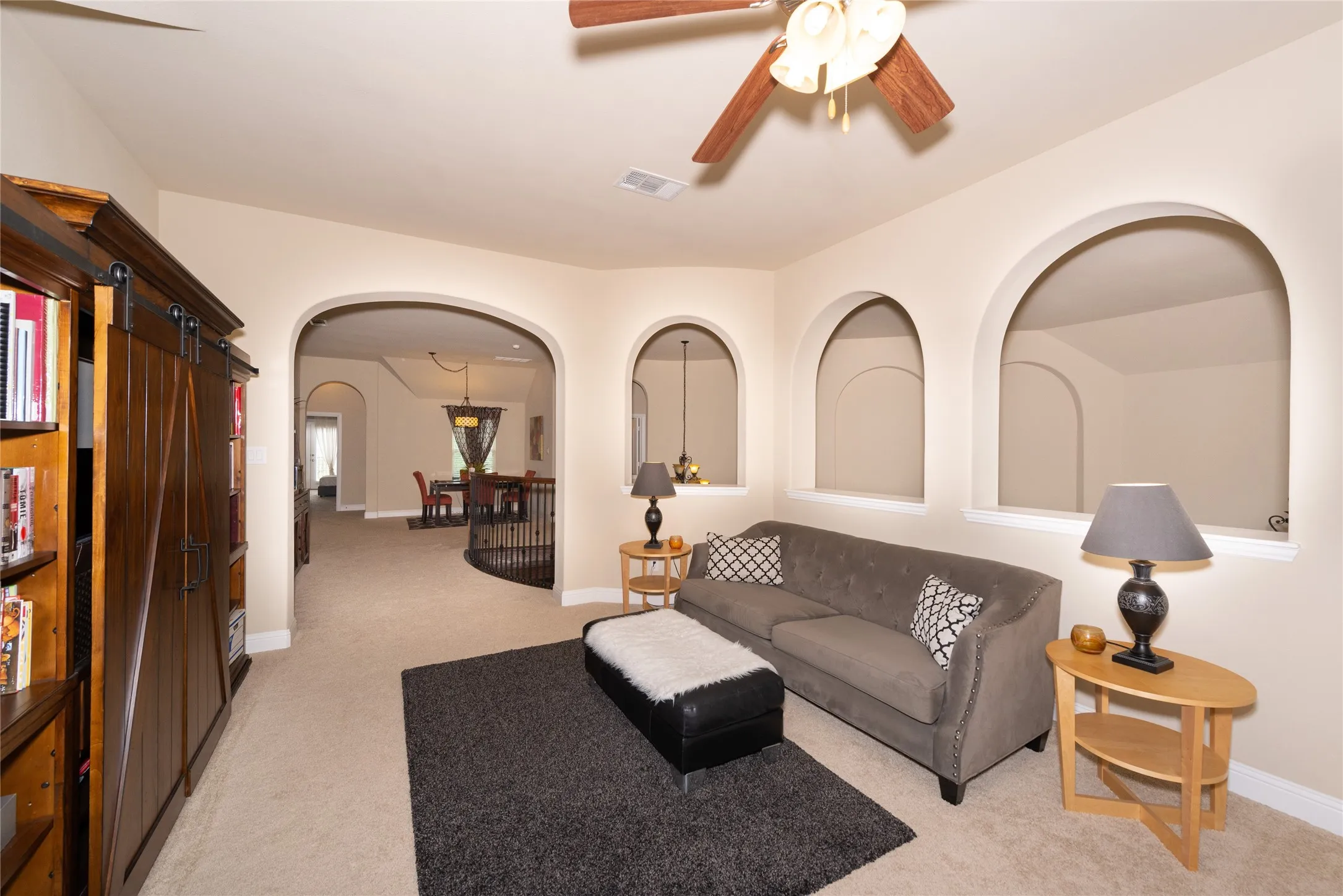 Carpeted room featuring multiple arched wall openings, a ceiling fan, and recessed lighting