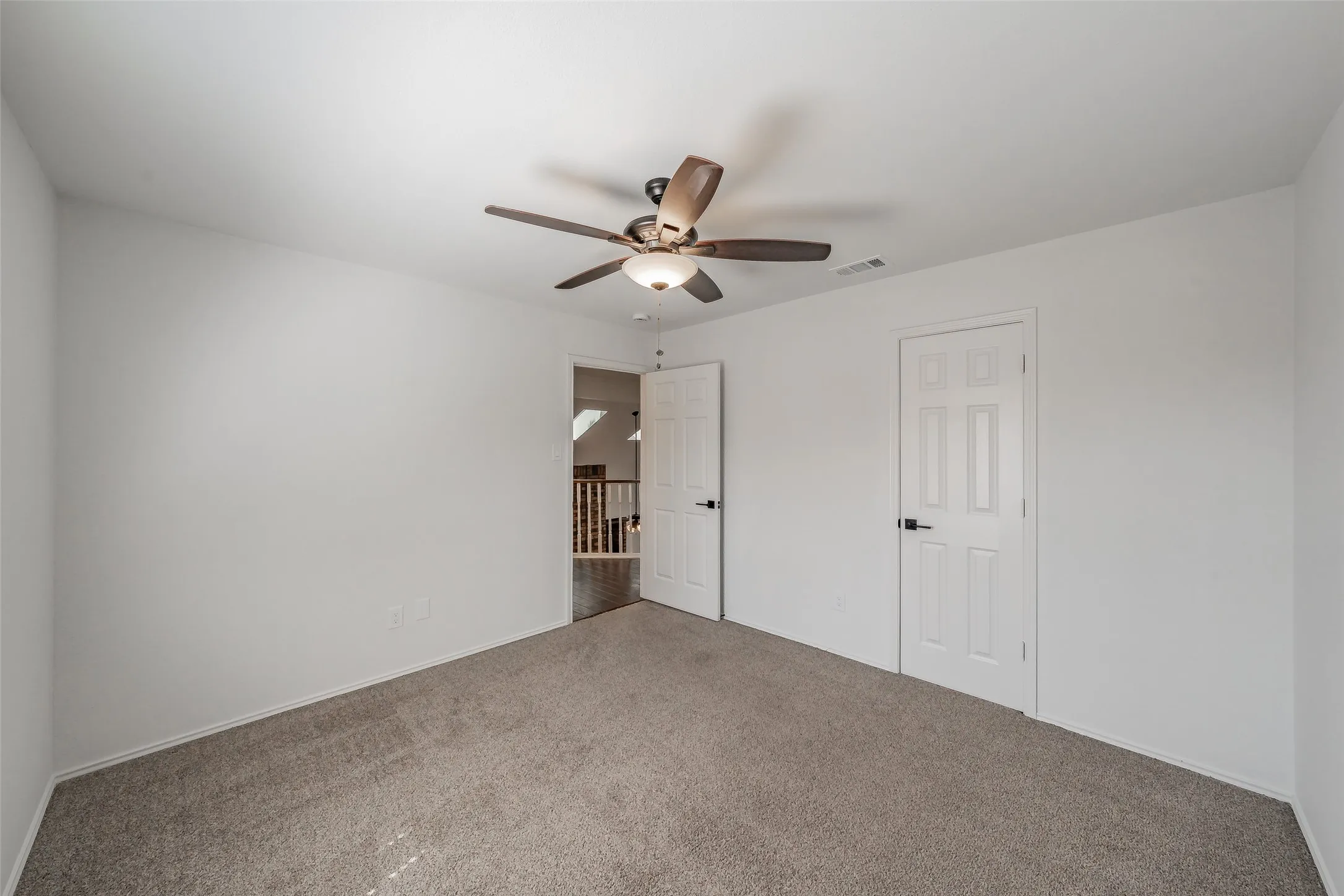 Secondary bedroom with carpet, ceiling fan, and walk in closet
