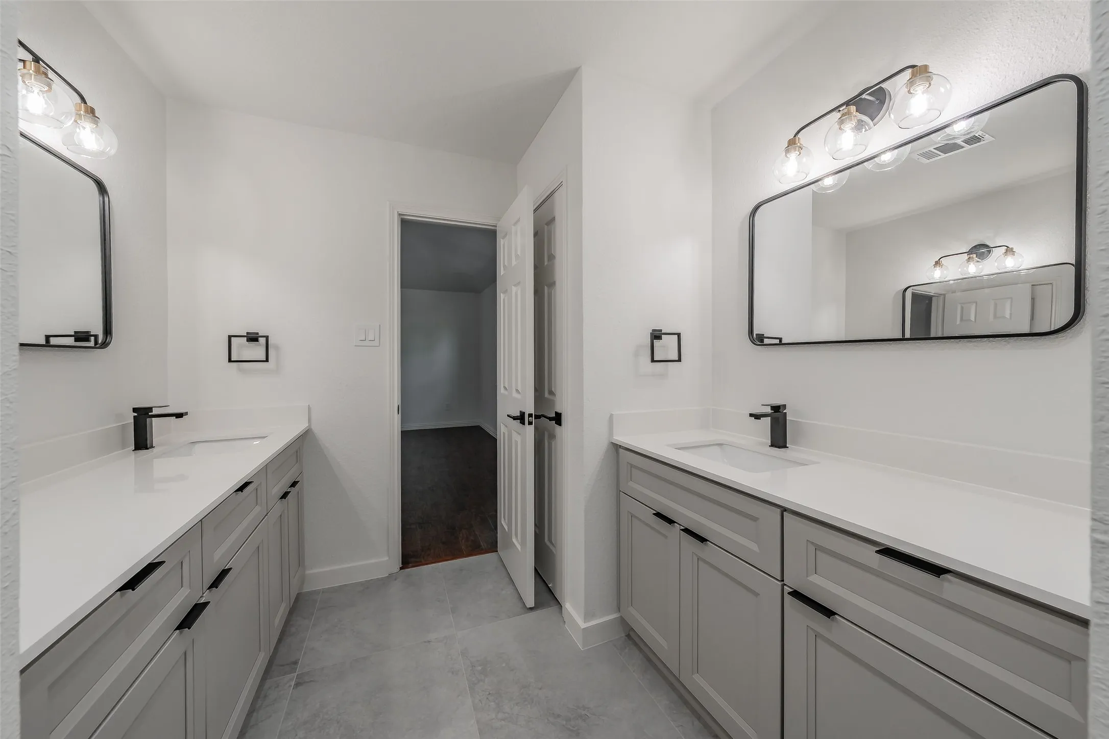 Dual vanity with undermount sinks, white countertops, and matte black fixtures