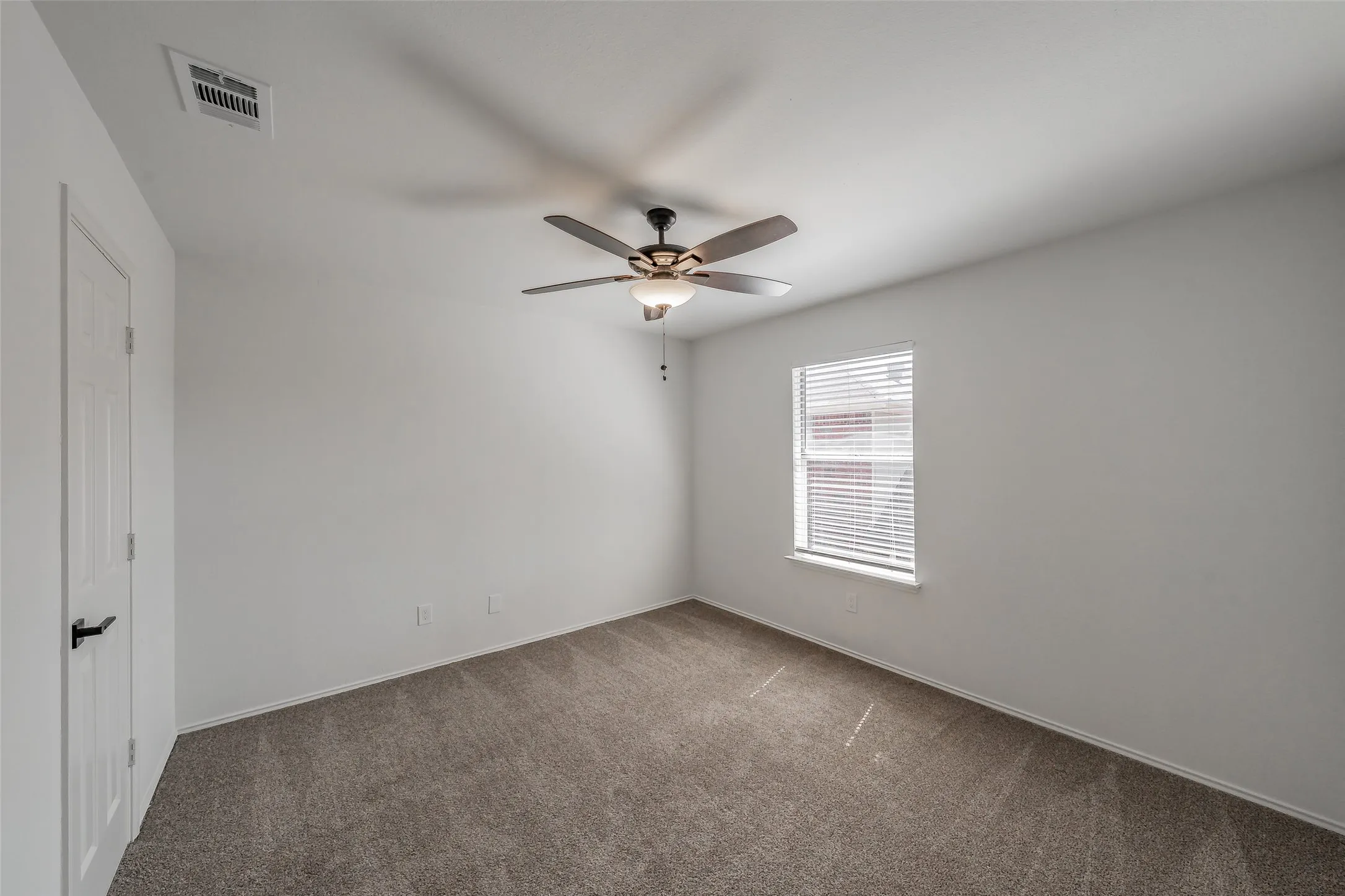 Secondary bedroom with carpet, ceiling fan, and walk in closet