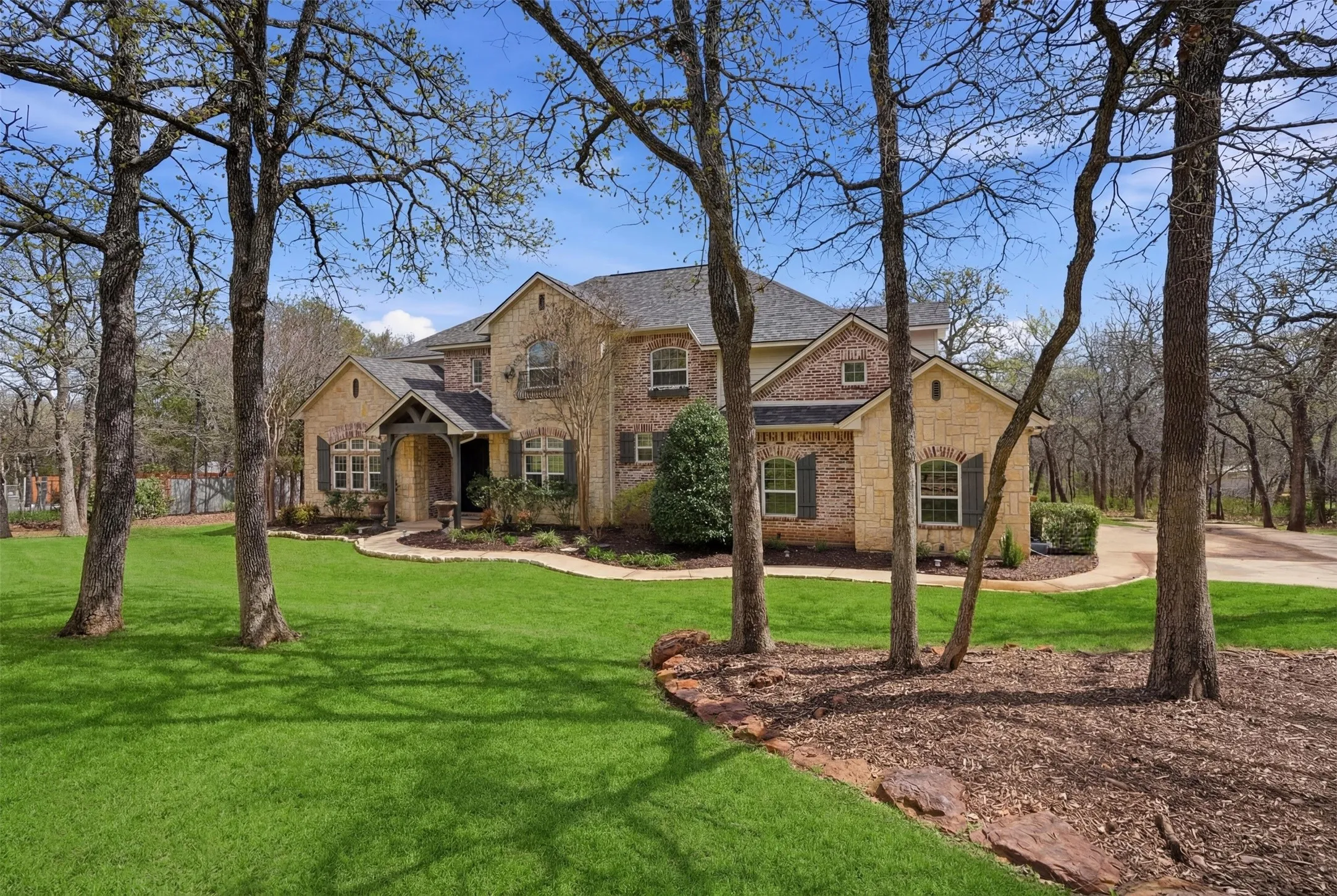Two-story residence featuring a combination of brick and stone exterior, gabled rooflines, and a covered entry
