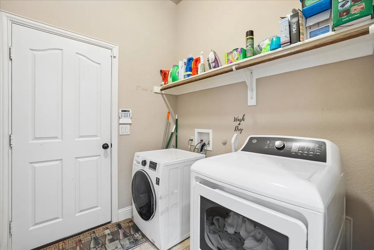 Laundry area with white paneled door and overhead shelving
