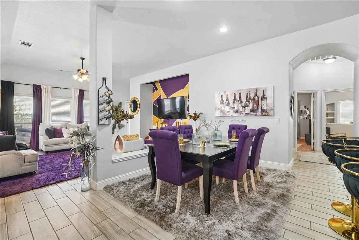 Open-concept living and dining areas featuring tile flooring, an arched doorway, and recessed lighting