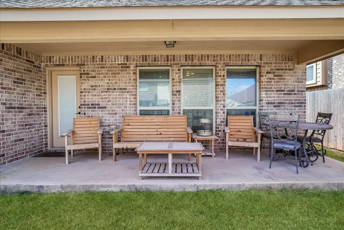 Covered concrete patio featuring a brick exterior and multiple windows