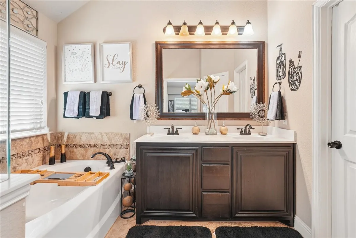Dual vanity with dark wood-finish cabinetry, white countertop, and individual bronze-tone faucets