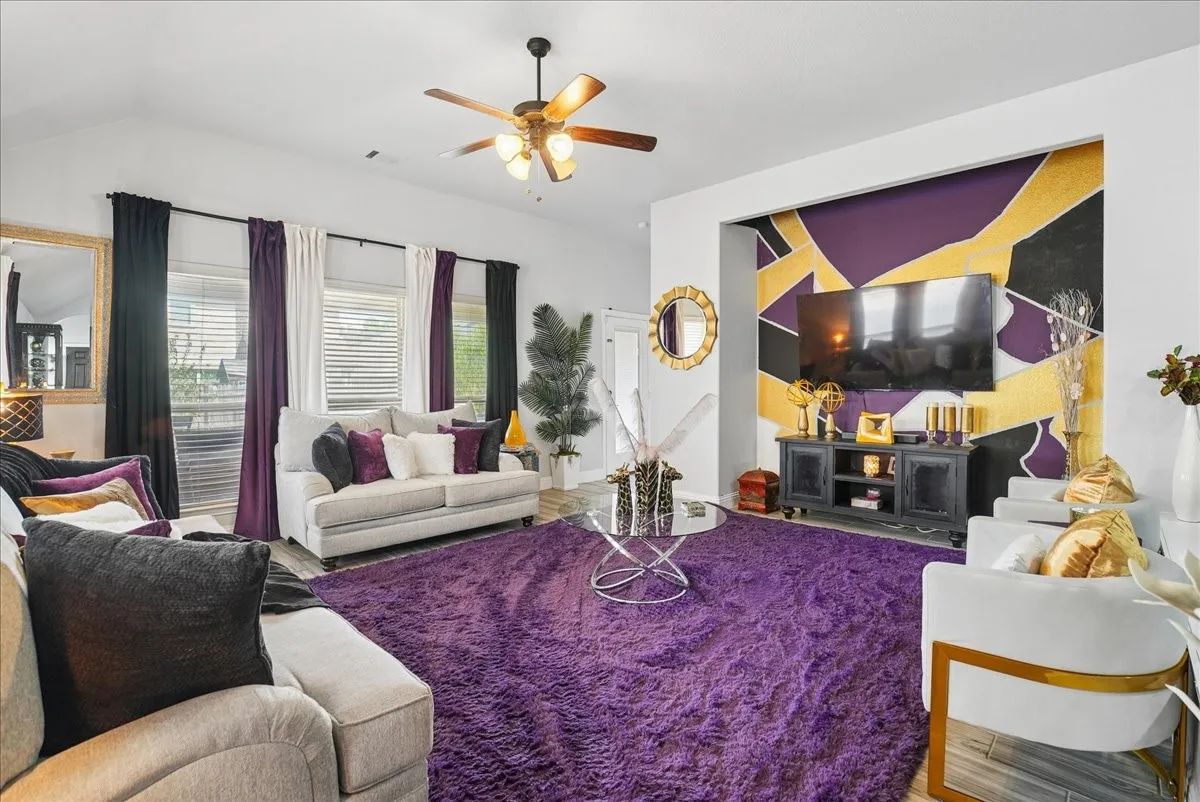 Vaulted ceiling, ceiling fan with integrated lighting, multiple windows with blinds, built-in media niche, and wood-finish flooring