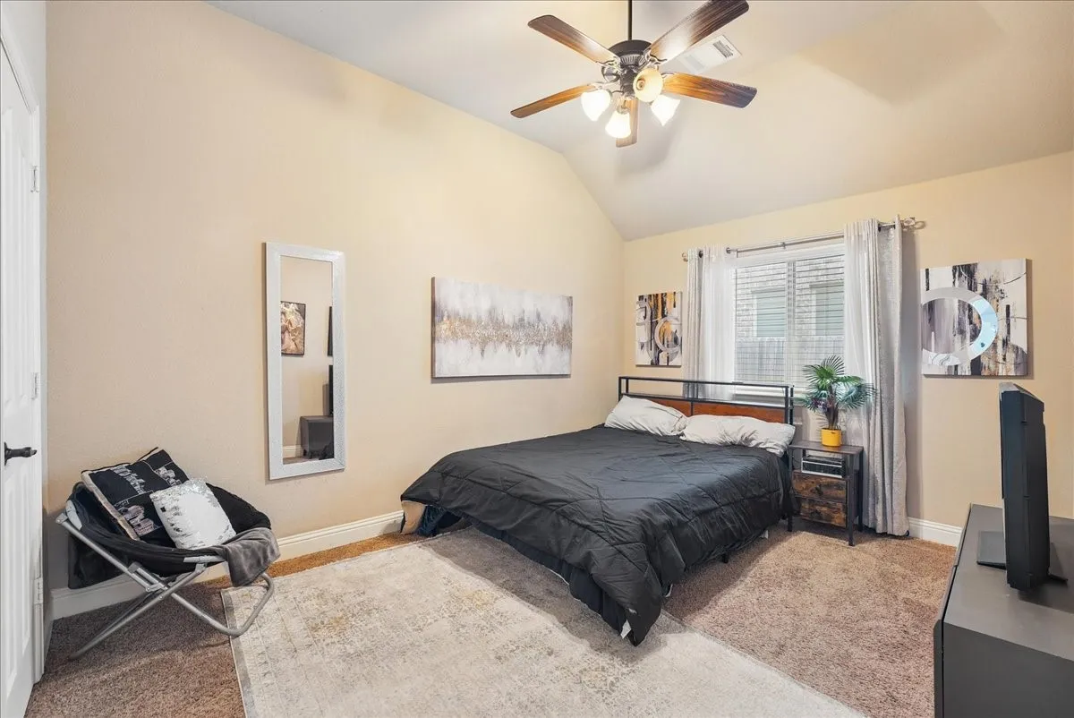 Vaulted ceiling, ceiling fan with integrated lighting, window with blinds, wood-finish flooring, and built-in door