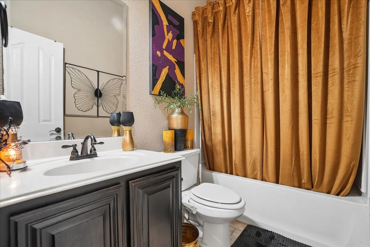 Vanity with dark wood cabinetry, white countertop with integrated sink, and an oil-rubbed bronze faucet