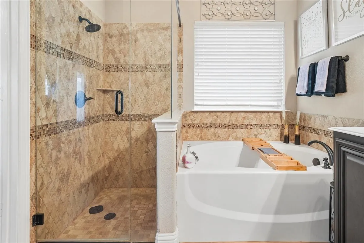 Enclosed shower with decorative tile work, a built-in shelf, and oil-rubbed bronze fixtures