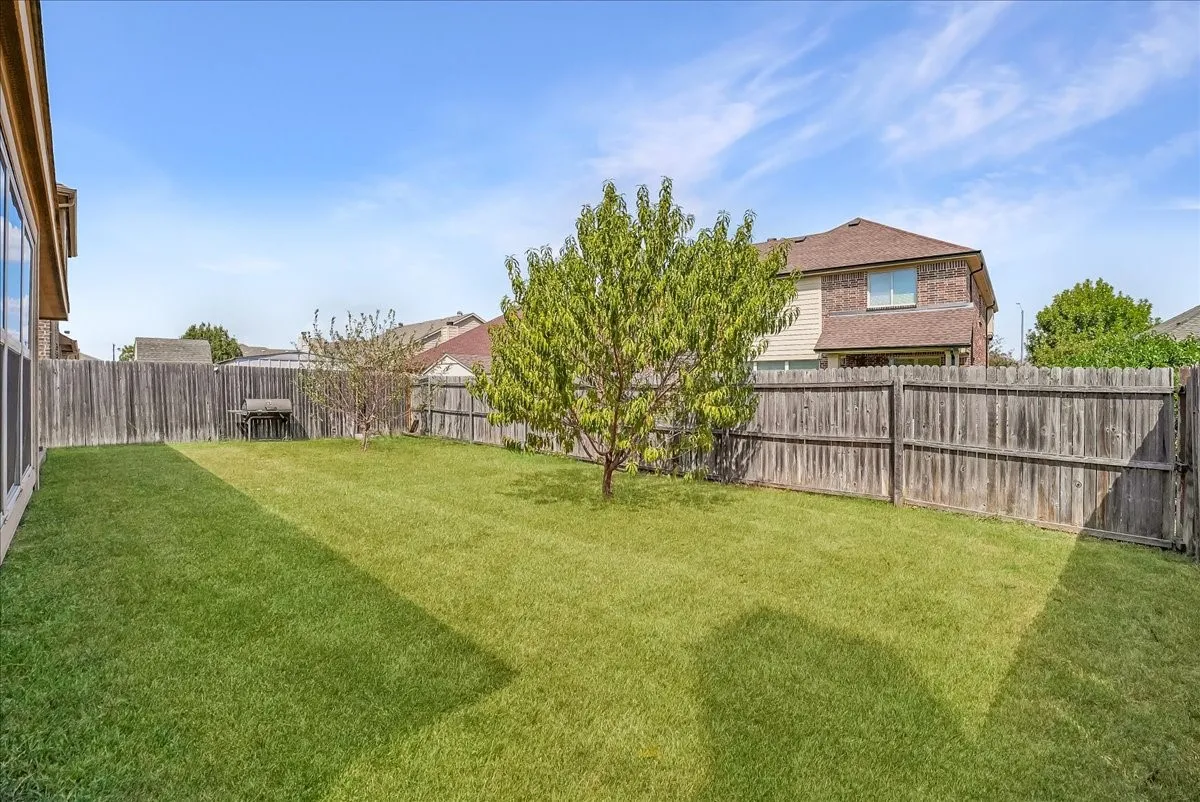 Expansive fenced yard featuring a manicured lawn and a mature tree